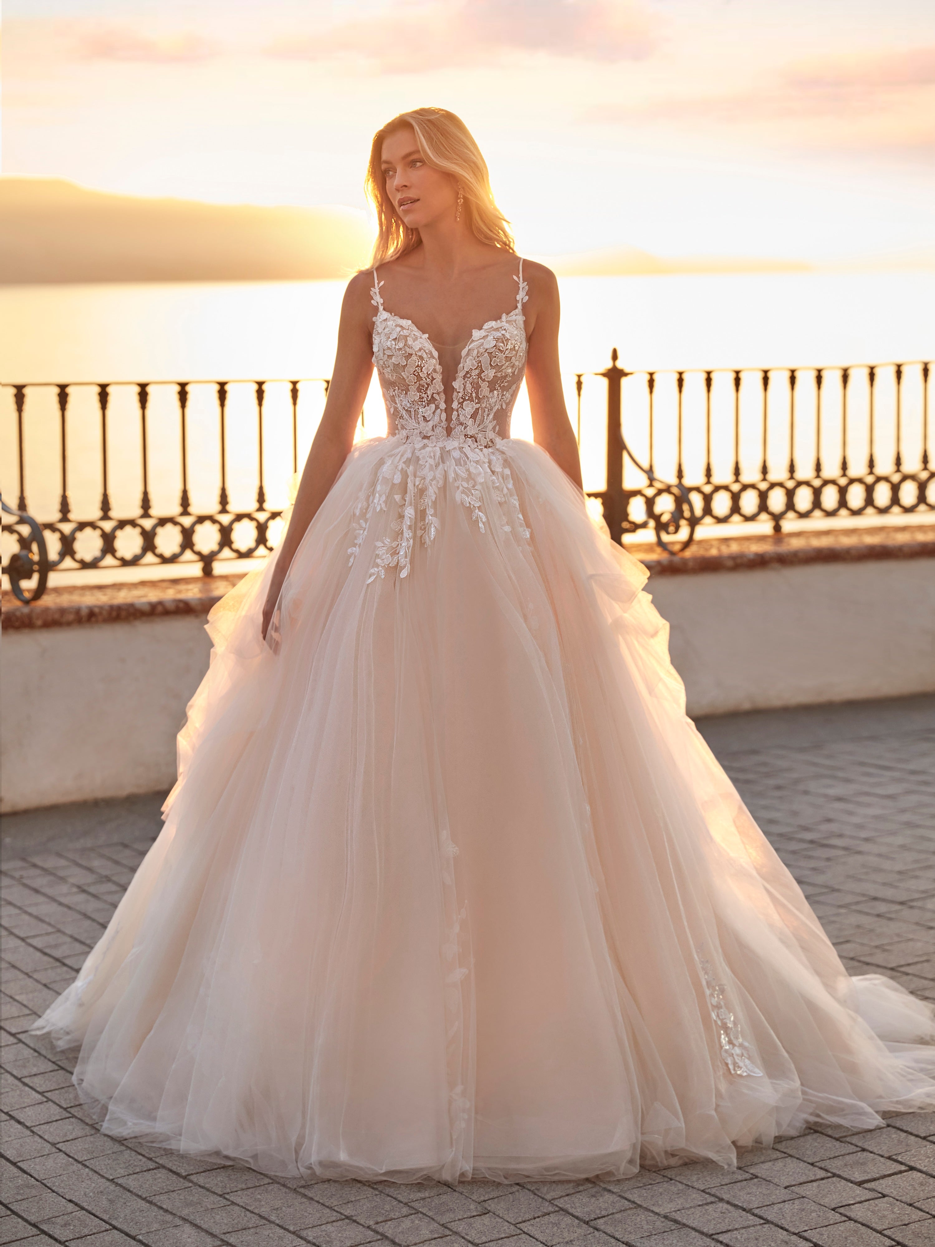 Woman in a wedding dress standing outdoors with a sunset background