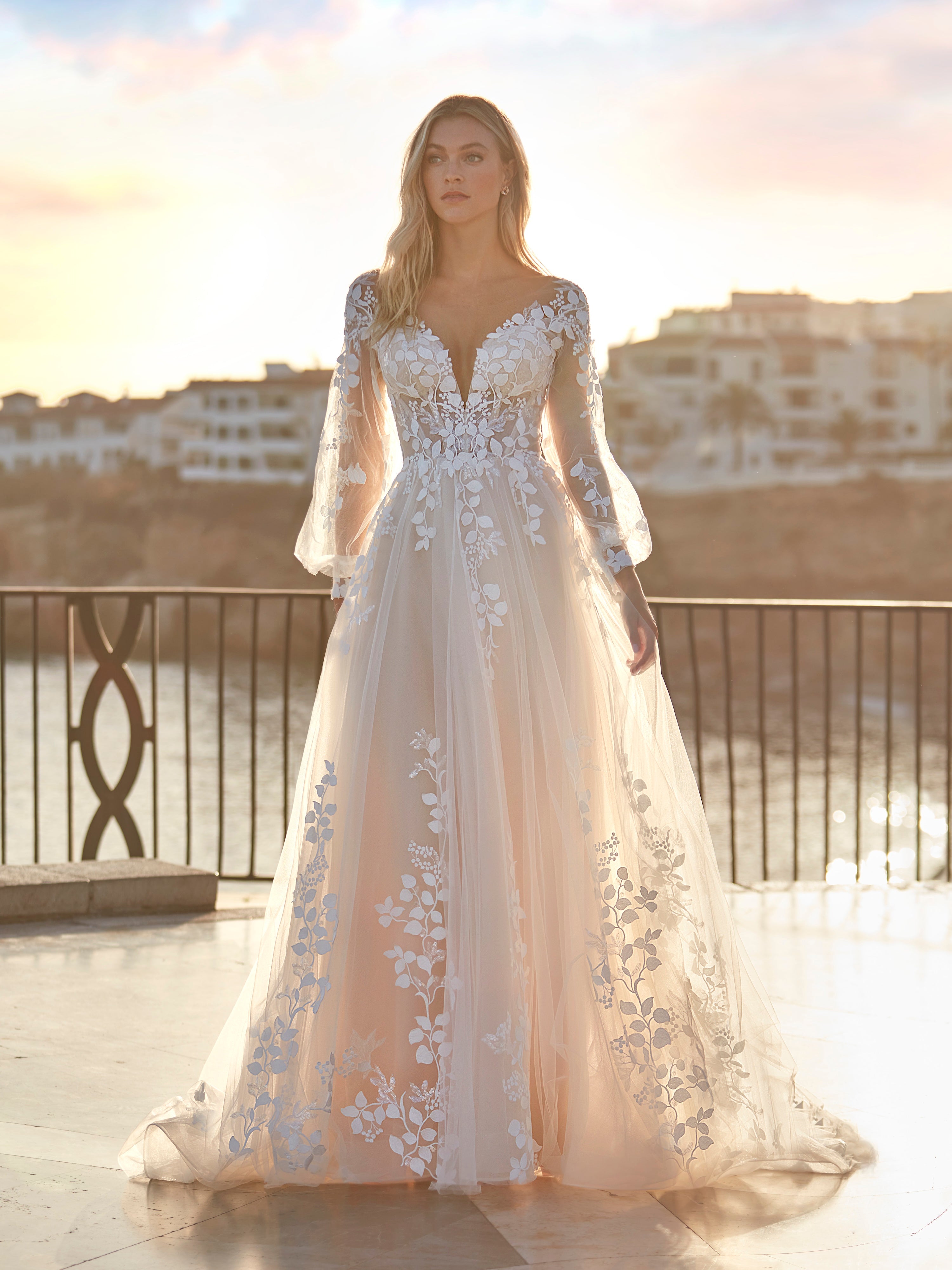 Woman in a white floral dress standing on a balcony with a scenic background