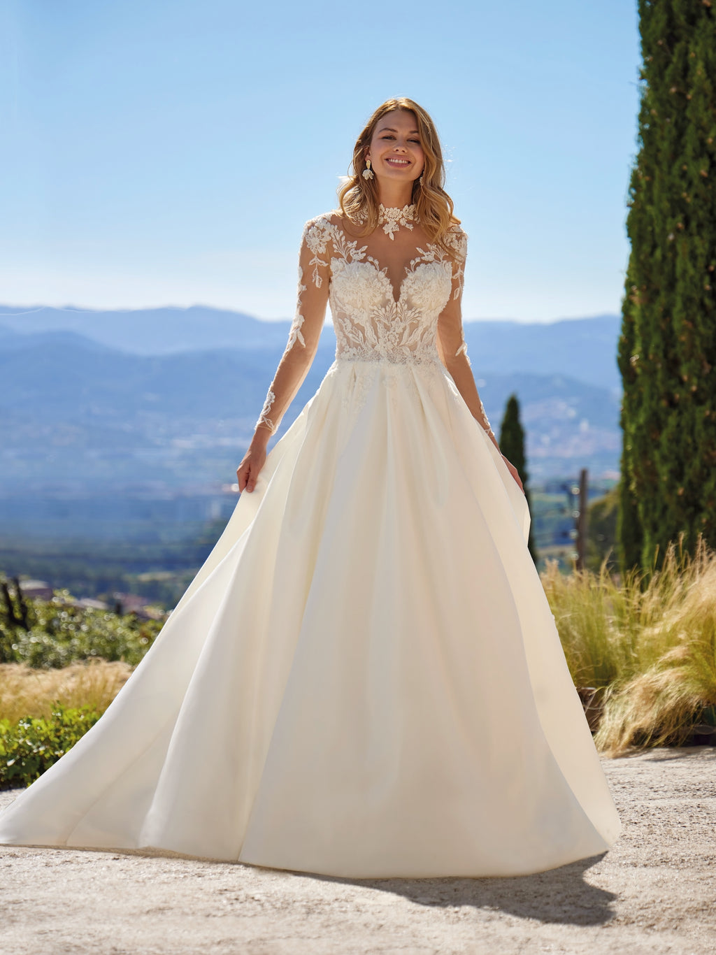 Woman in a white wedding dress standing outdoors with mountains in the background