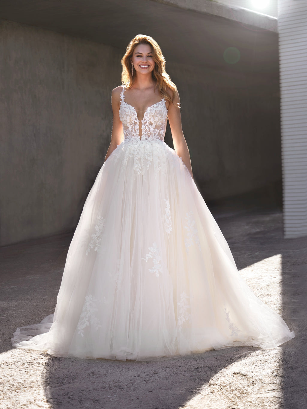 Woman wearing a white wedding dress with lace details in an urban setting.