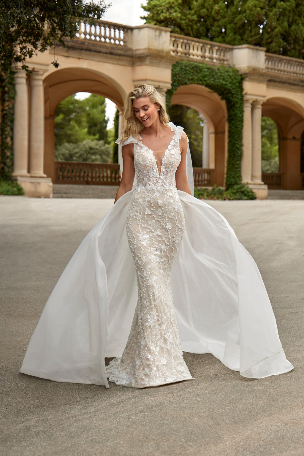 Woman in a white wedding dress standing in front of classical architecture.