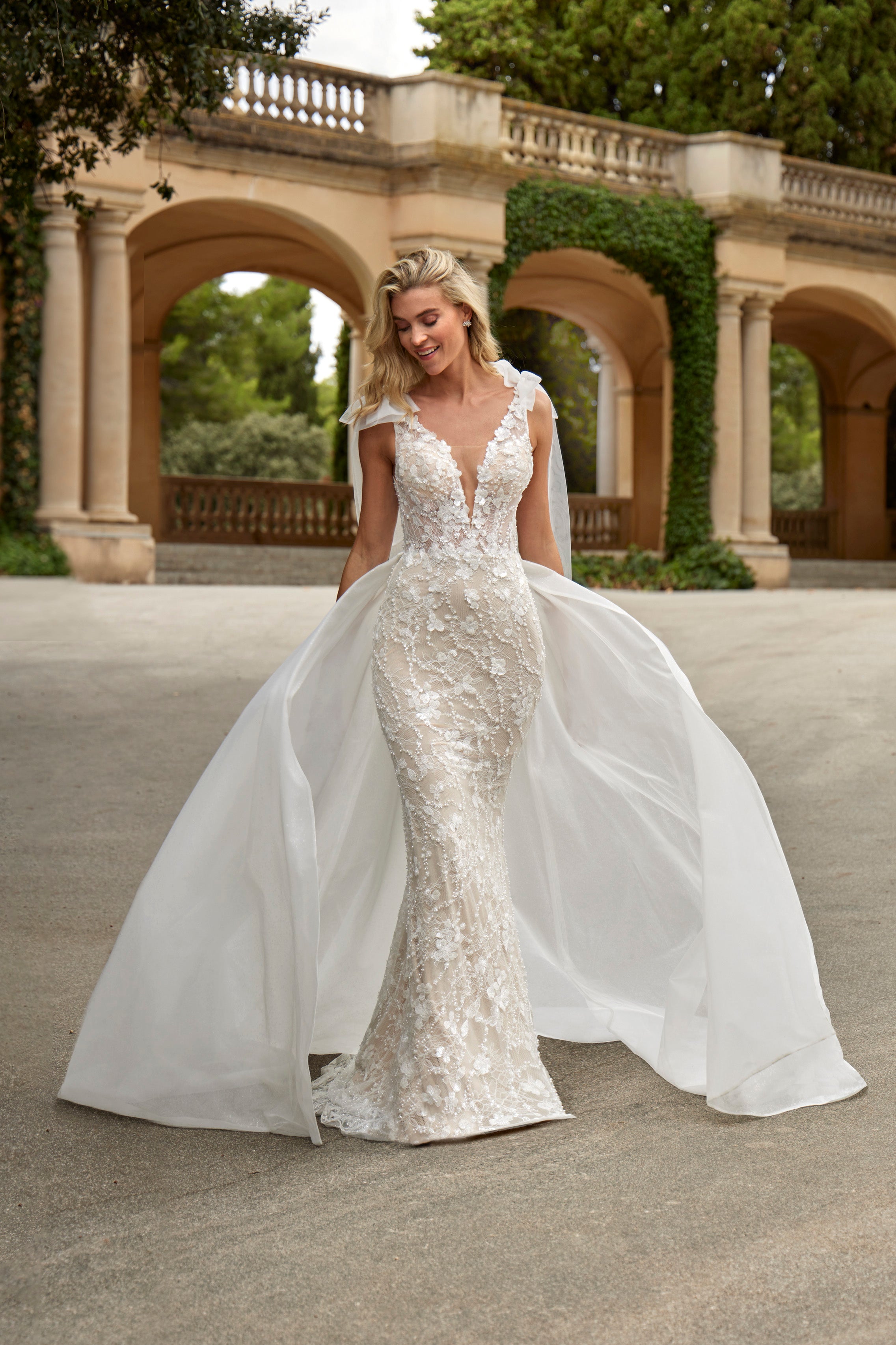 Woman in a white wedding dress standing in front of classical architecture.