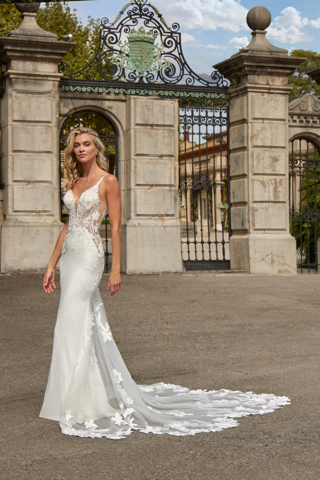 Woman in a white wedding dress standing in front of an ornate gate.