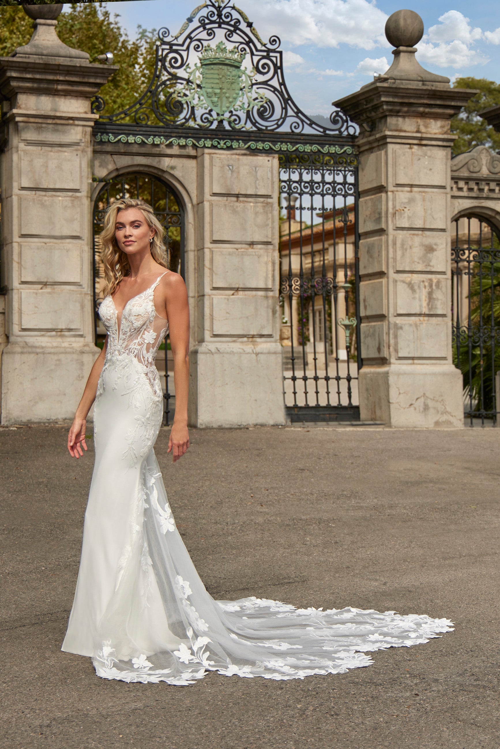 Woman in a white wedding dress standing in front of an ornate gate.