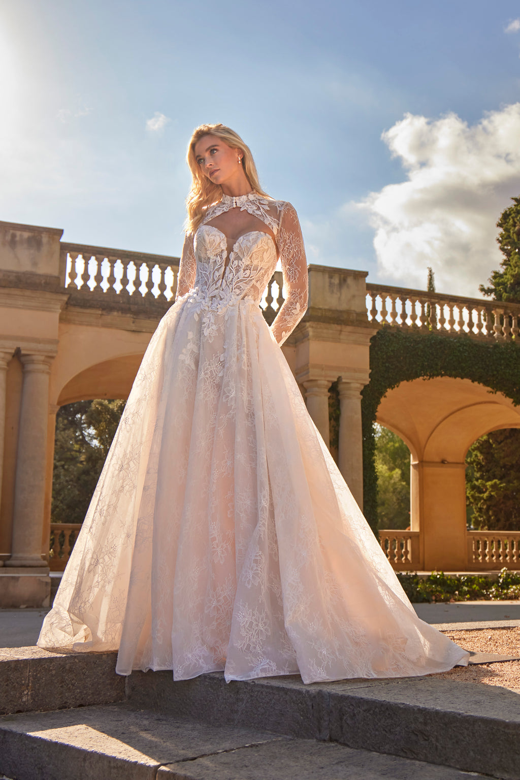 Woman in a white wedding dress standing in an outdoor setting with classical architecture.