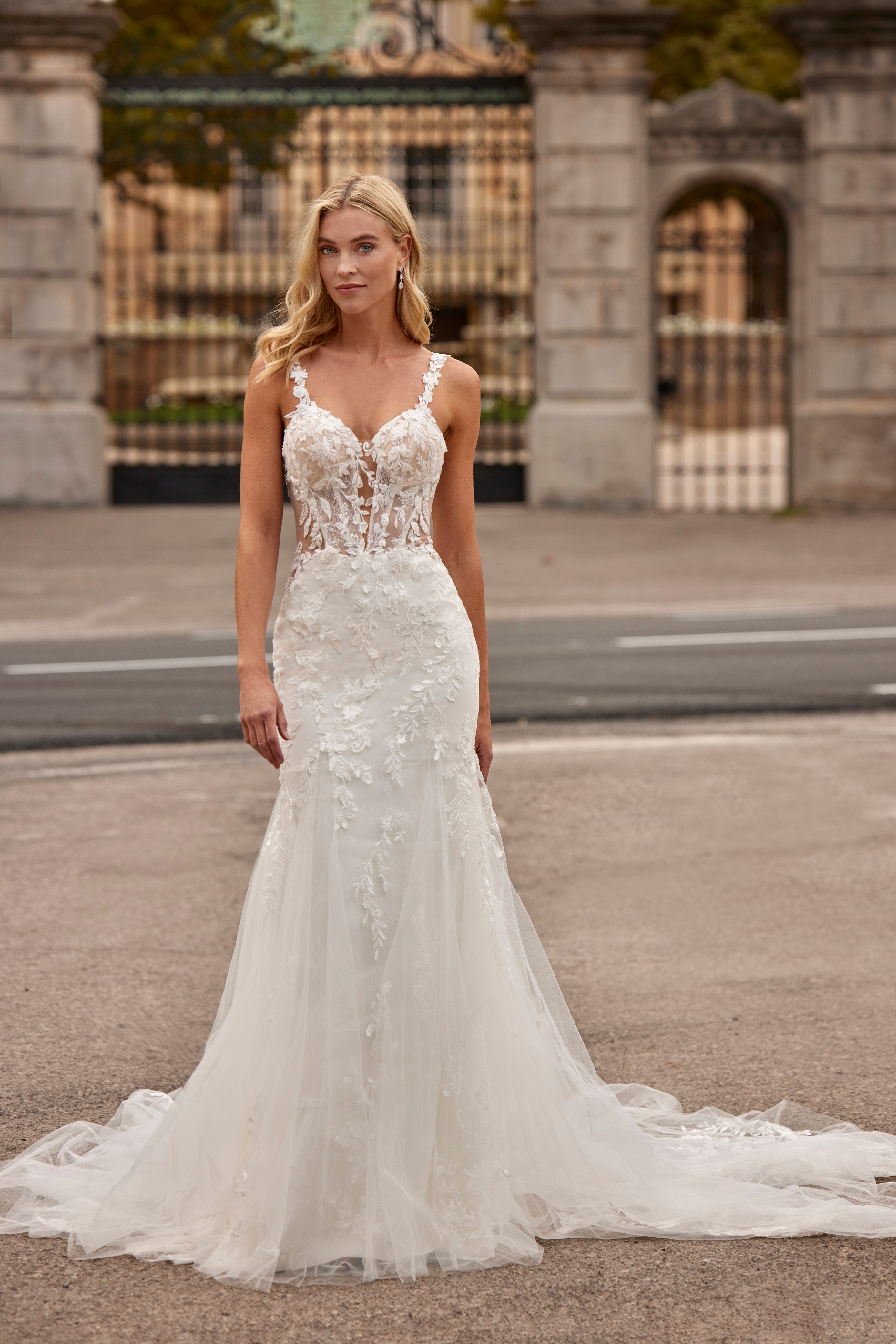 Woman in a white wedding dress standing in front of a stone building.