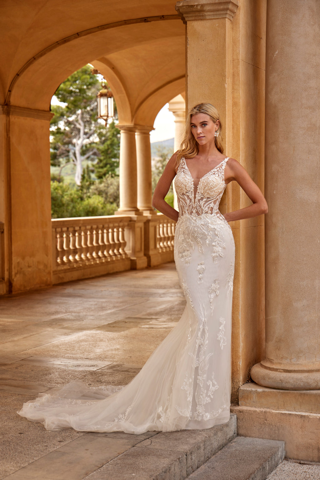 Woman in a white wedding dress standing in an elegant outdoor setting with columns.