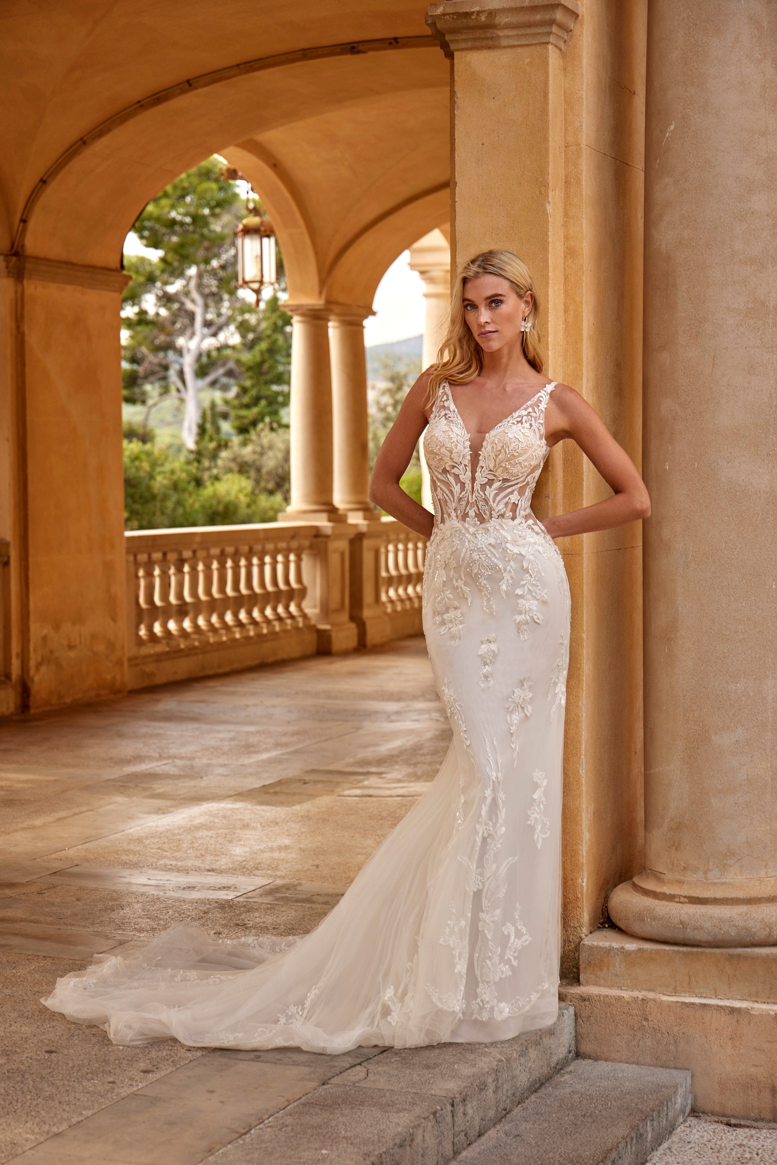 Woman in a white wedding dress standing in an elegant outdoor setting with columns.