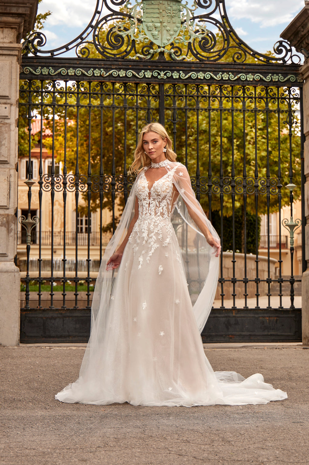Woman in a white wedding dress standing in front of an ornate metal gate.