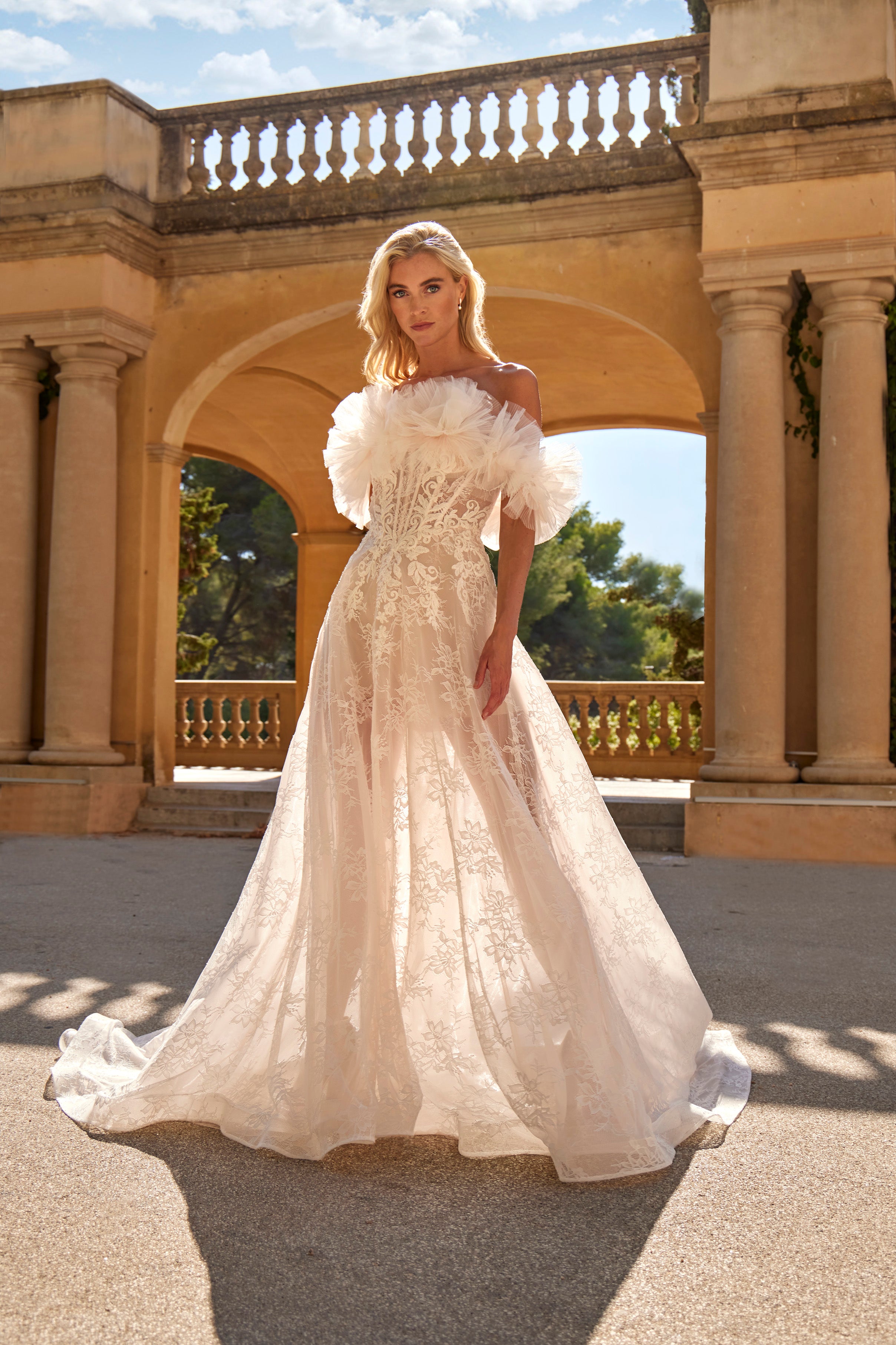 Woman in a white wedding dress standing in front of classical architecture.