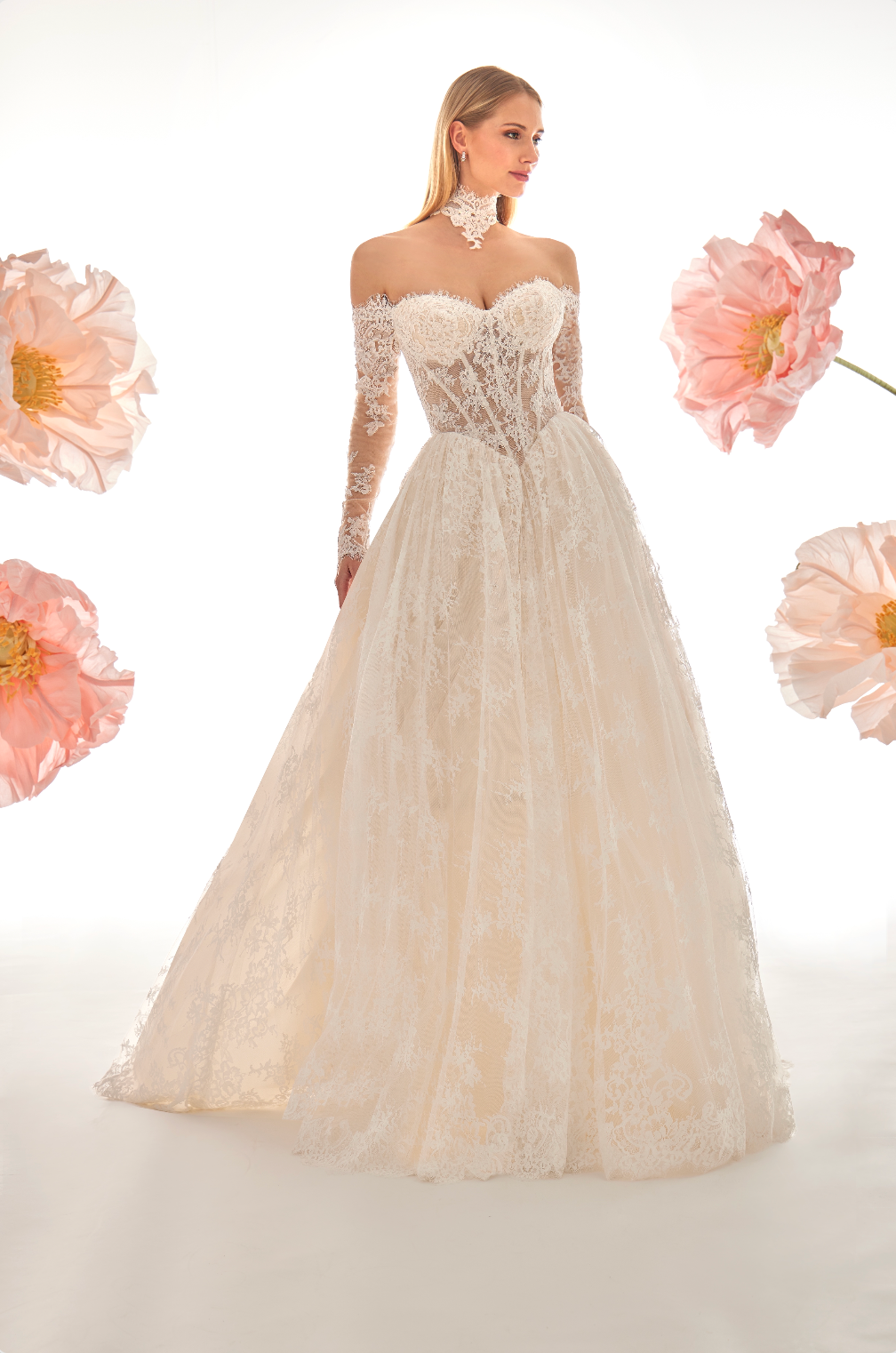 Elegant white lace wedding dress with long sleeves on a light background with pink flowers.