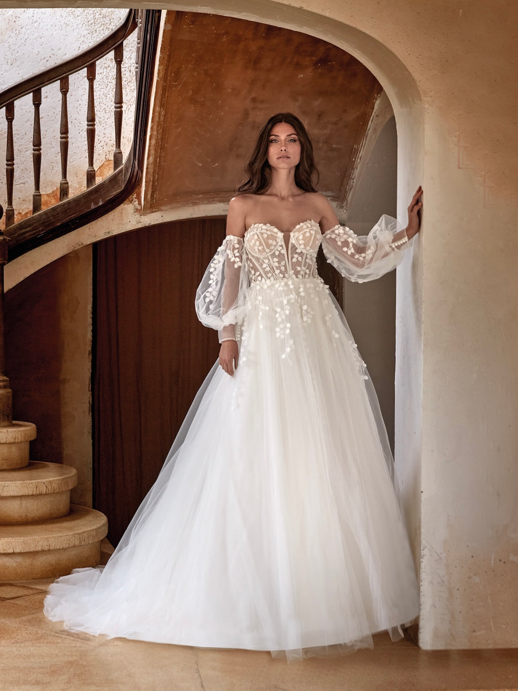 Woman in a white wedding dress standing in a staircase.