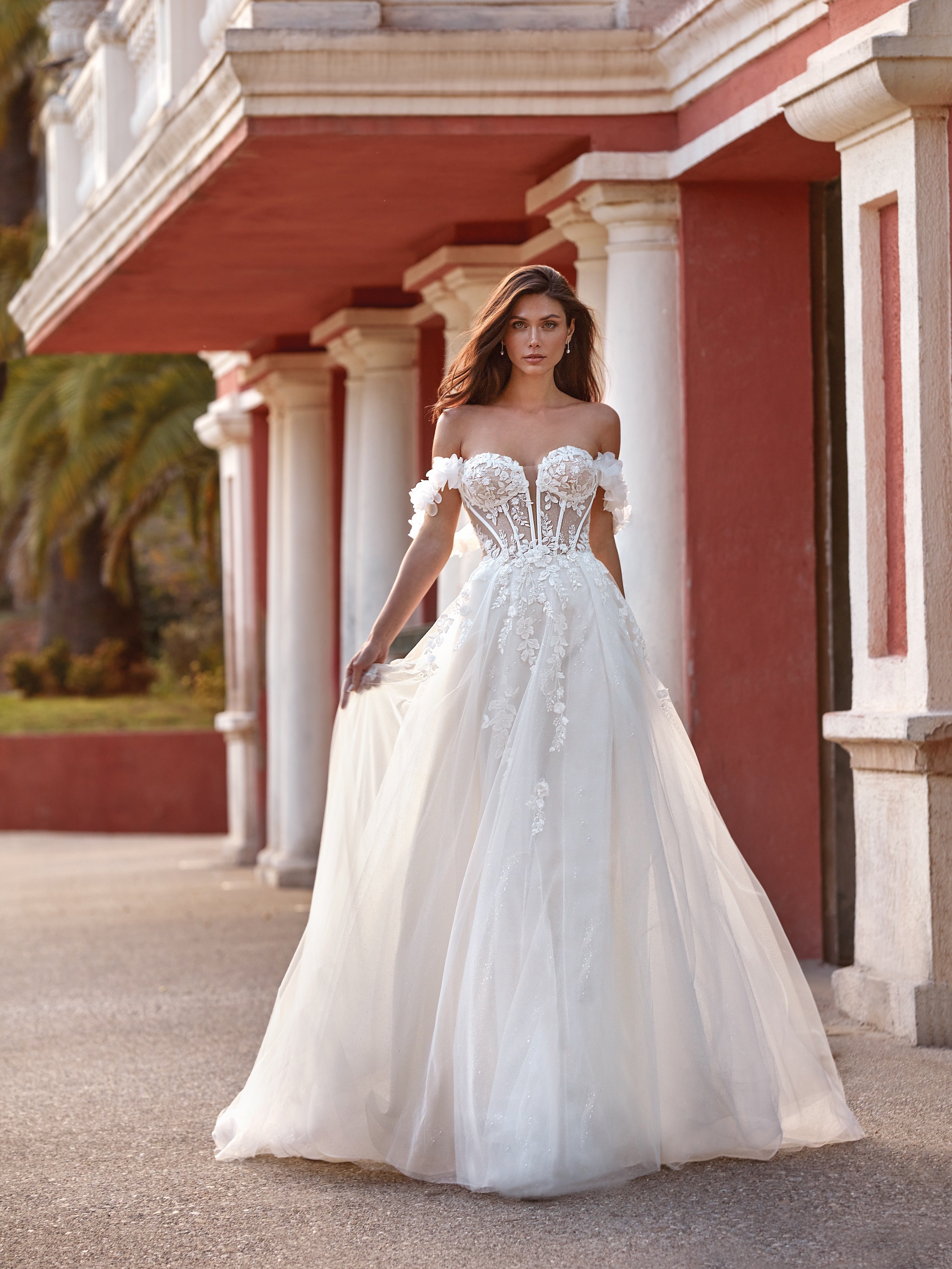 Woman in a white wedding dress standing in front of a classical building.