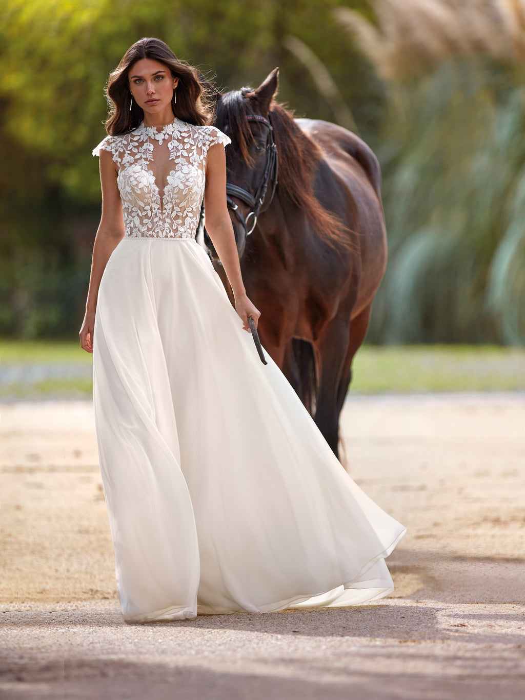 Woman in a white wedding dress with a horse in an outdoor setting