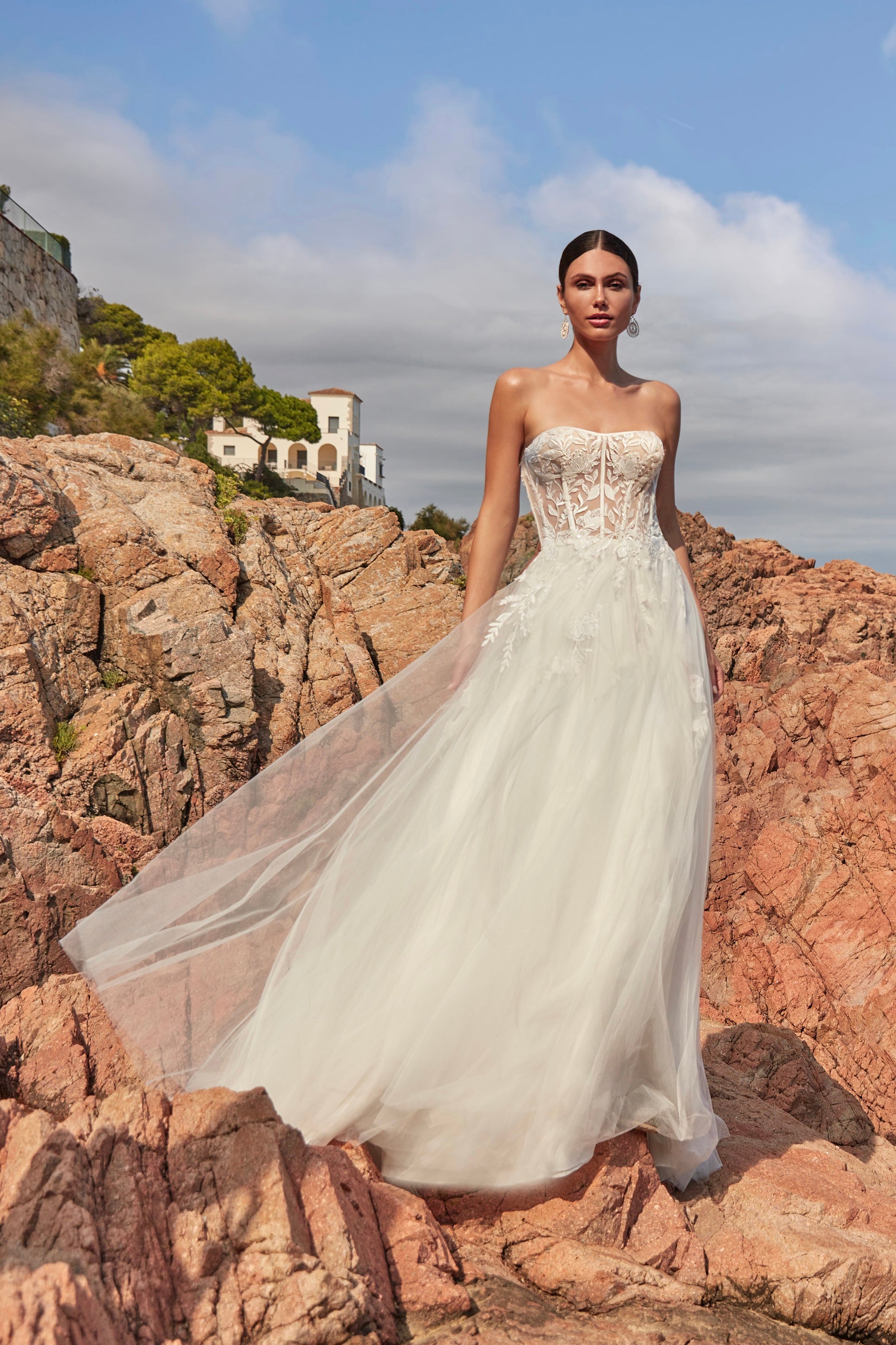 Woman in a strapless wedding dress standing on rocky terrain with a scenic background