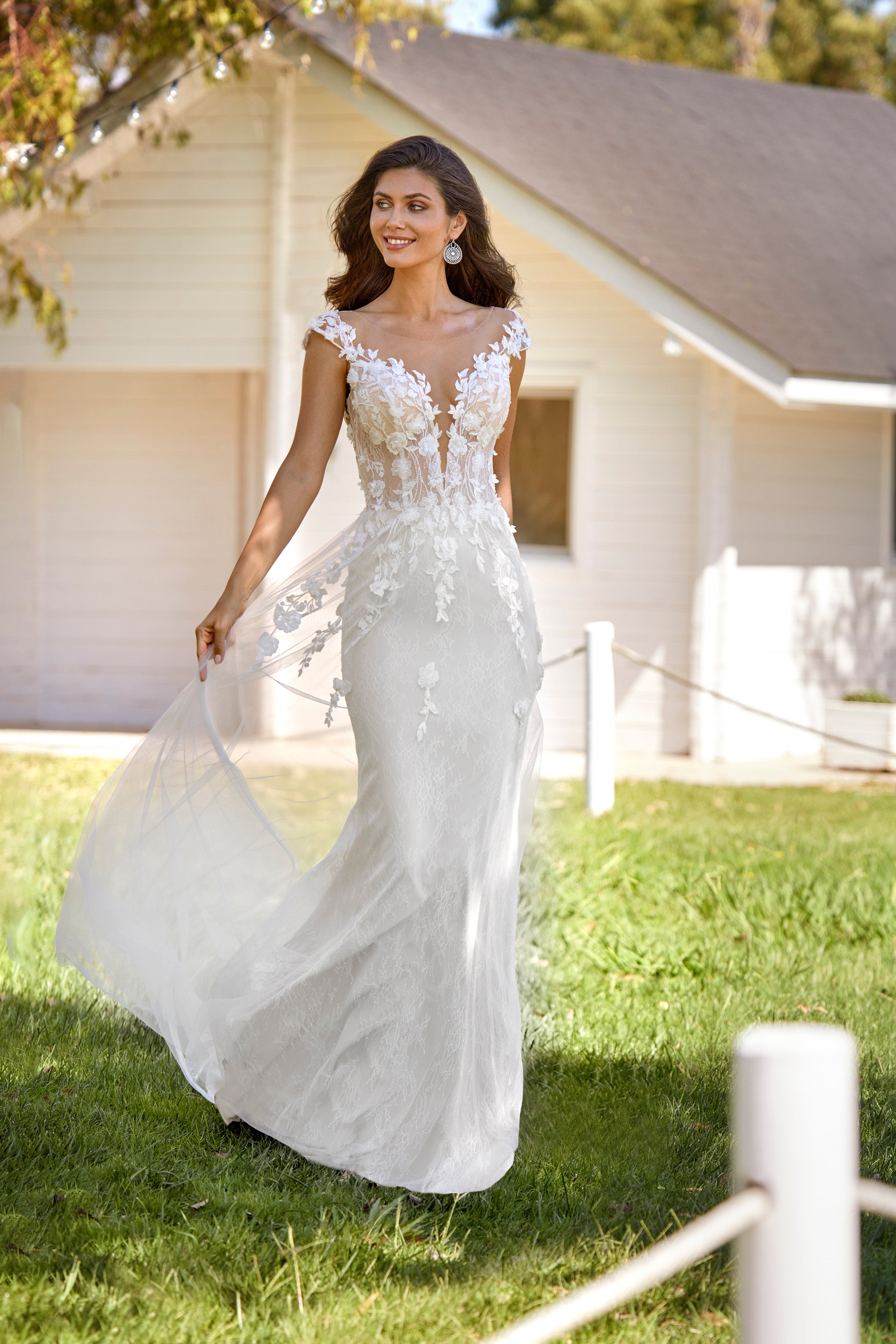 Woman in a white wedding dress standing outdoors with a house in the background