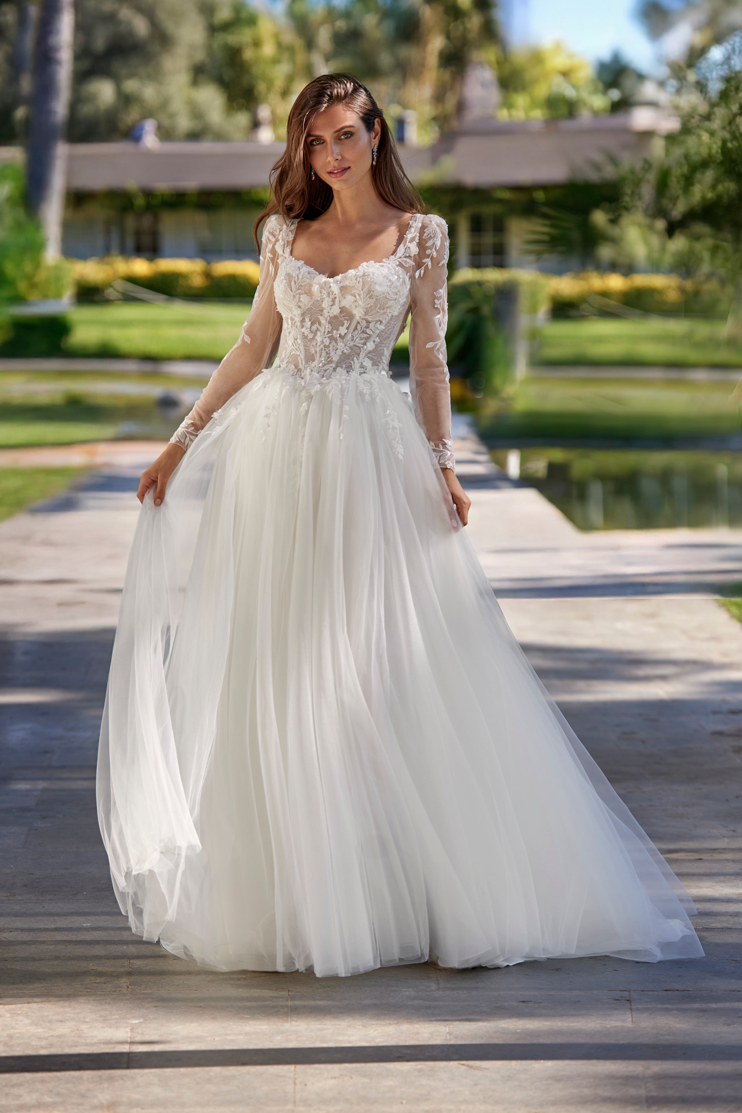 Woman in a white wedding dress standing on a wooden path with greenery in the background