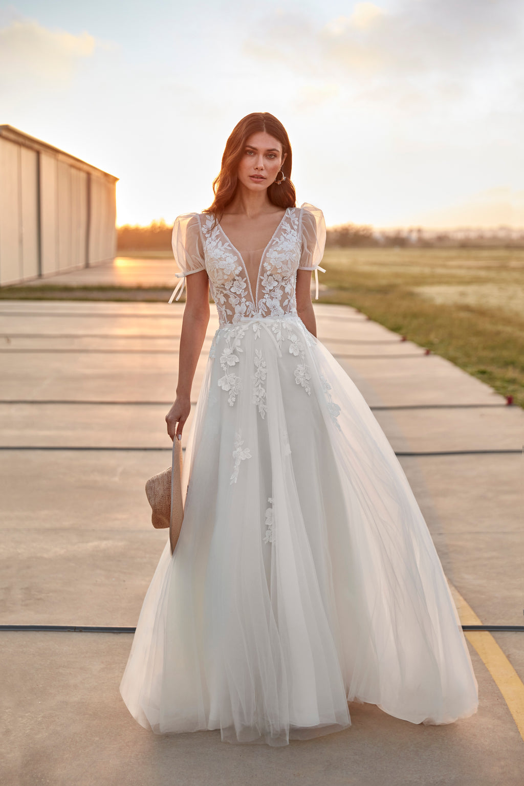Woman in a white wedding dress standing on a wooden platform with a scenic background.