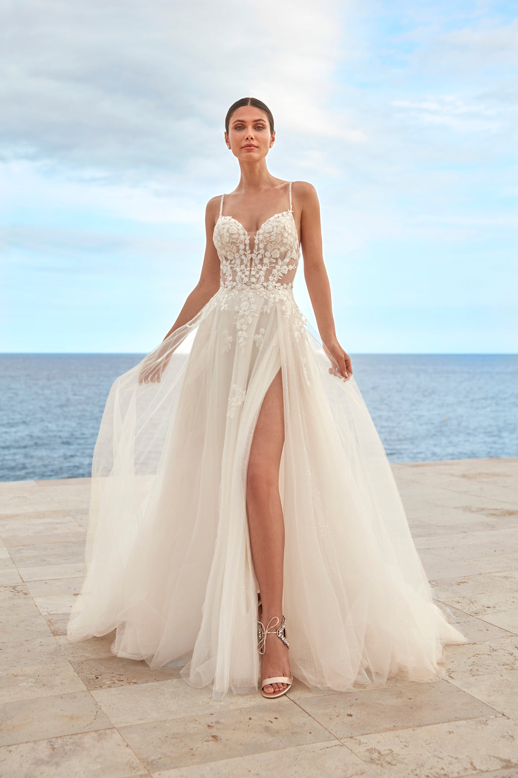 Woman in a white wedding dress standing on a beach with ocean view