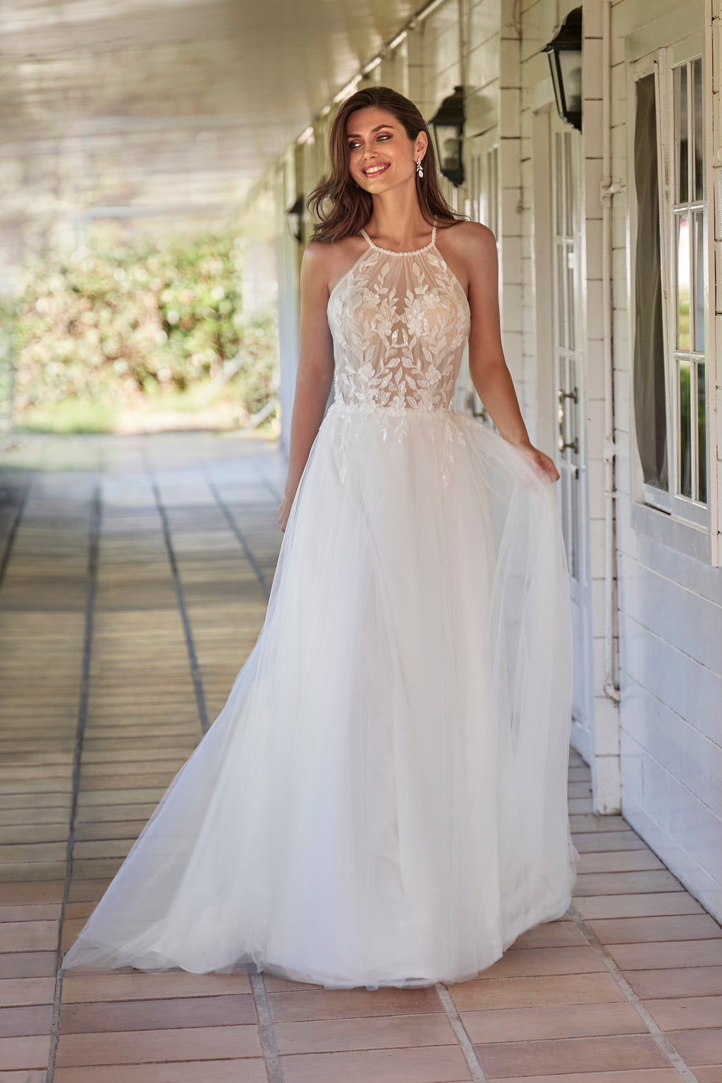 Woman in a white wedding dress standing on a wooden porch.