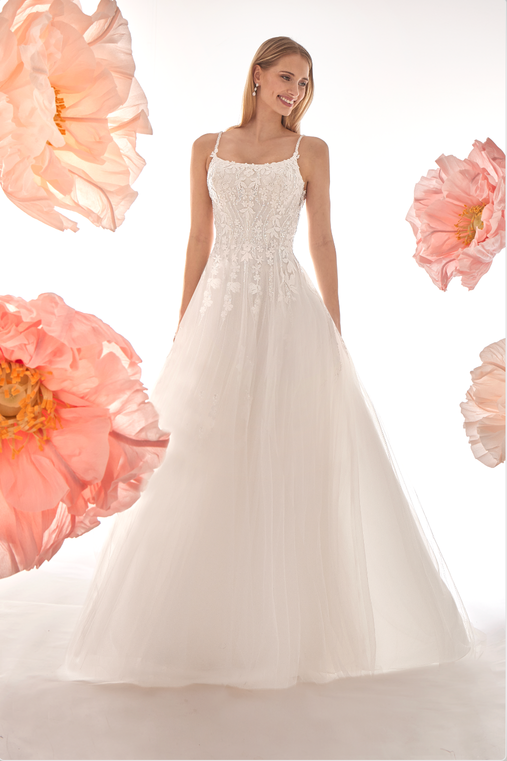 Woman wearing a white wedding dress with pink flowers in the background