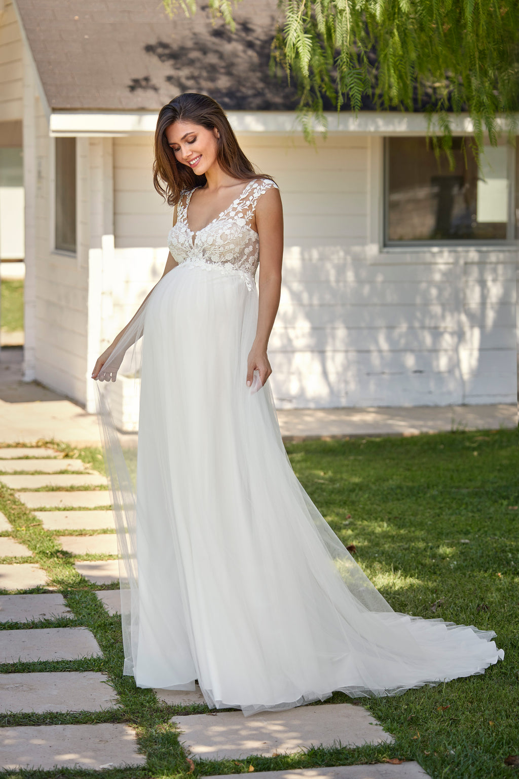Woman in a white wedding dress standing outdoors on a sunny day.