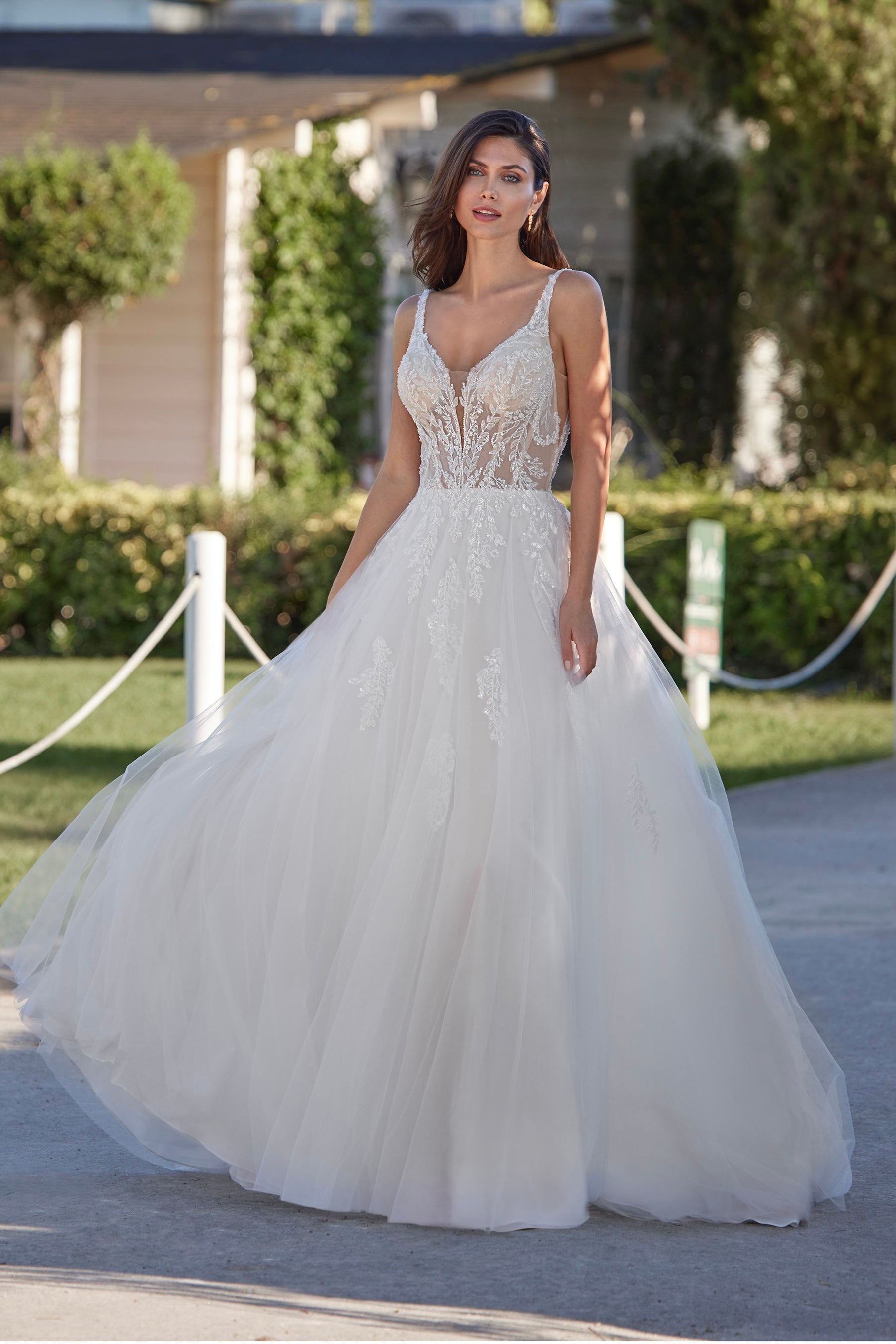Woman in a white wedding dress standing outdoors with greenery in the background