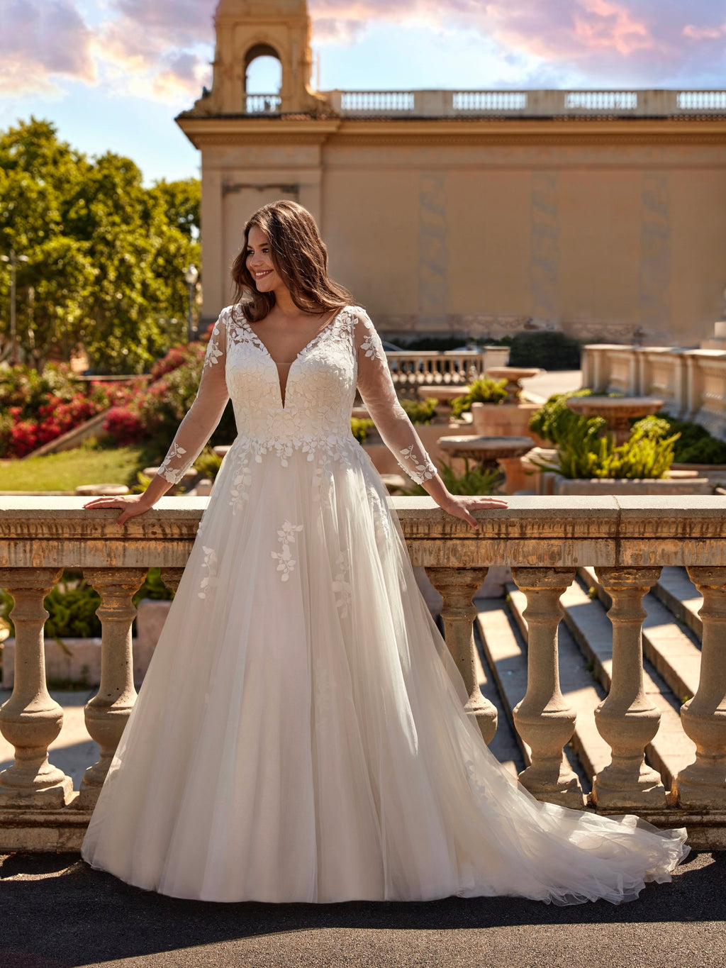Woman in a white wedding dress standing on a balcony with a scenic background