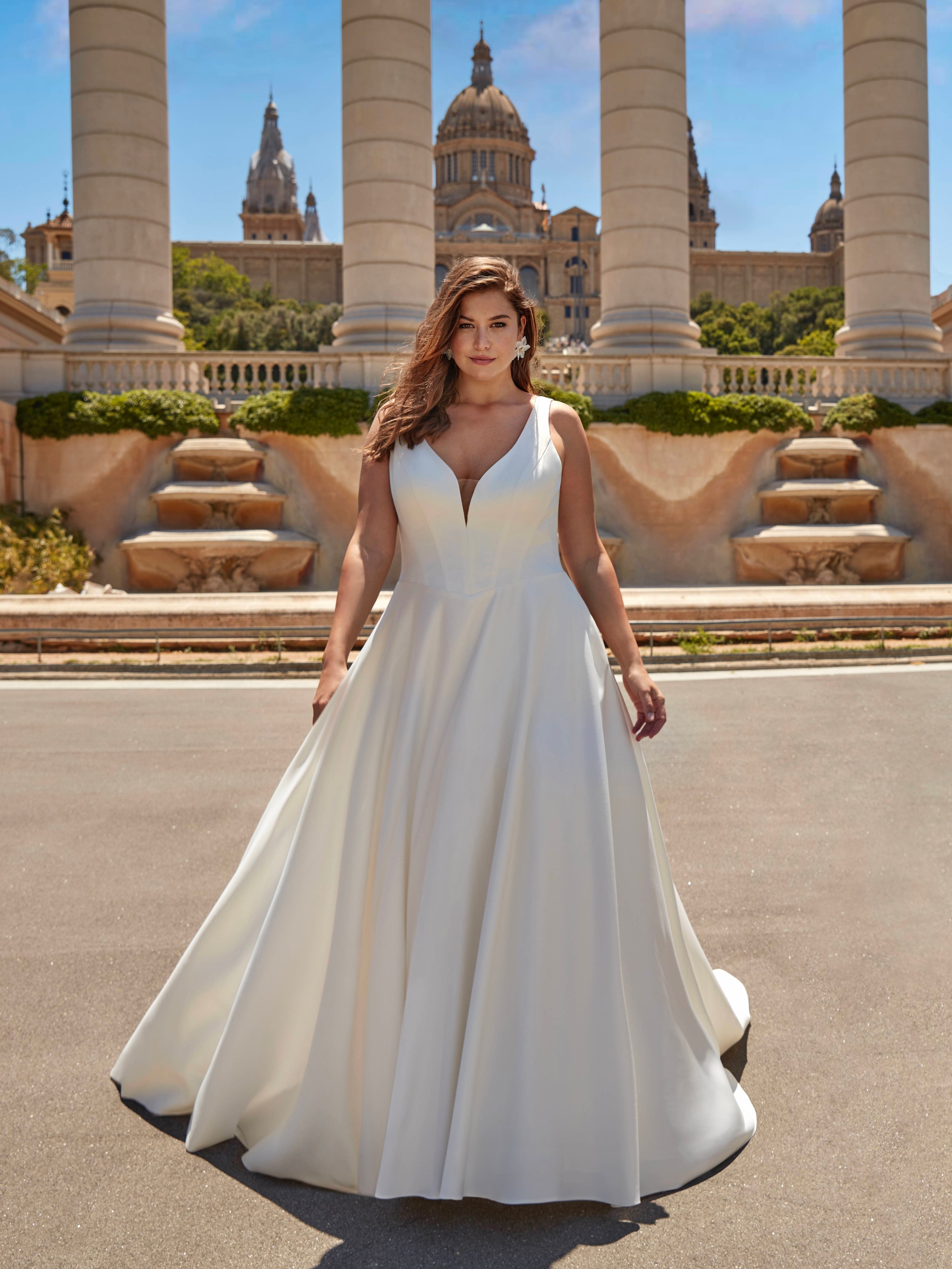 Woman in a white wedding dress standing in front of a historic building with columns.