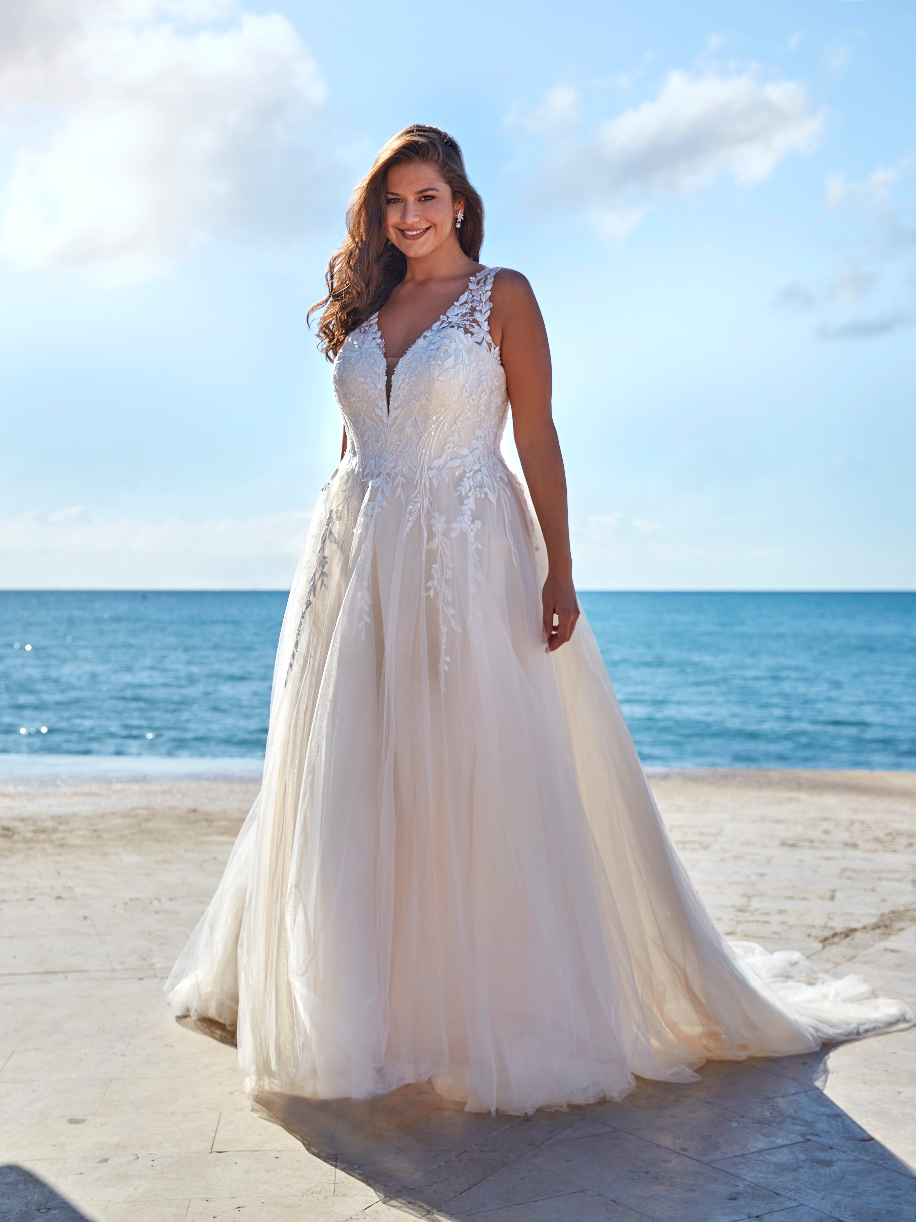 Woman in a white wedding dress in front of the ocean.