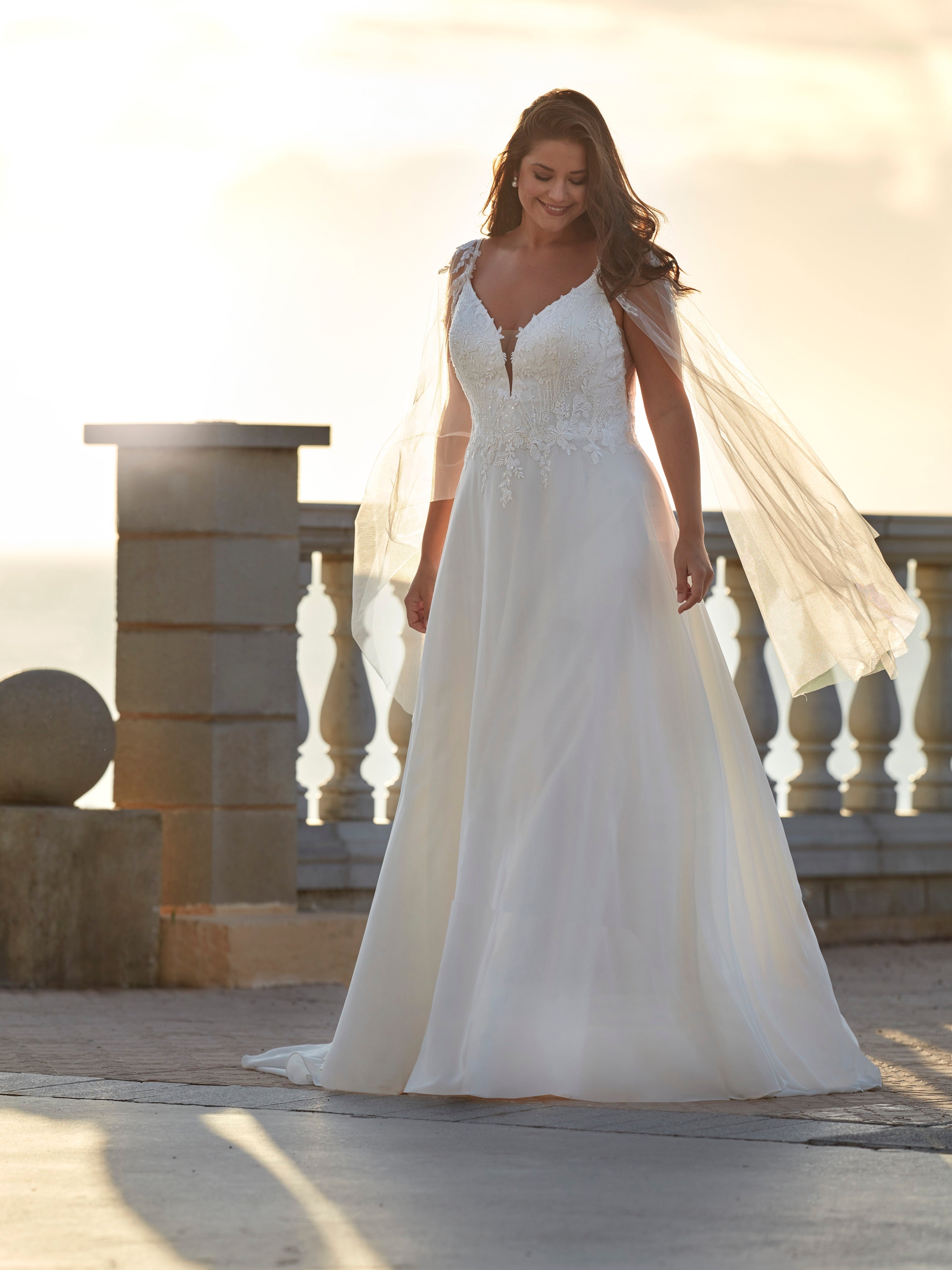 Woman in a white wedding dress standing on a balcony with a scenic background
