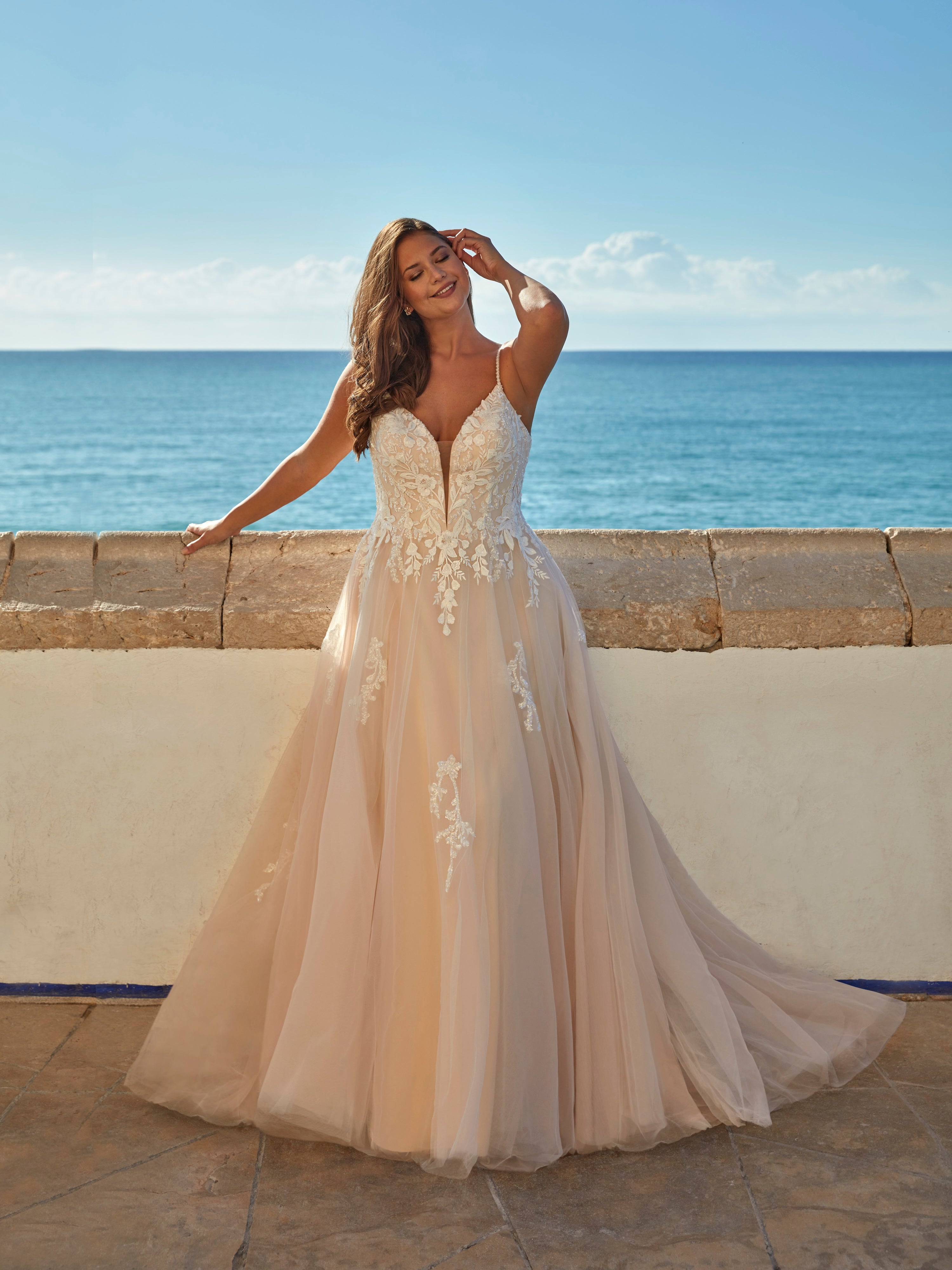 Woman in a wedding dress standing on a balcony with ocean view