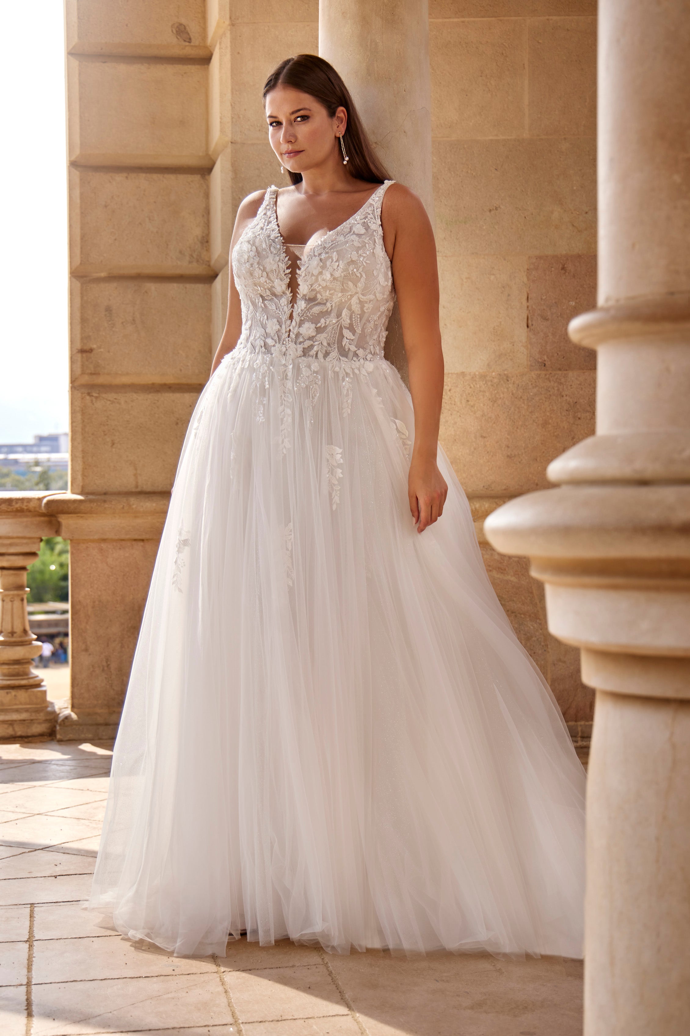 Woman in a white wedding dress standing in front of classical architecture.