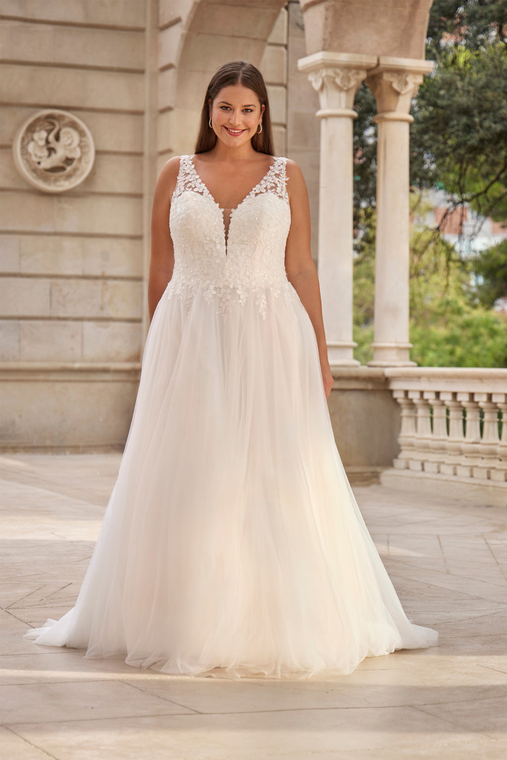 Woman in a white wedding dress standing outdoors with classical architecture in the background