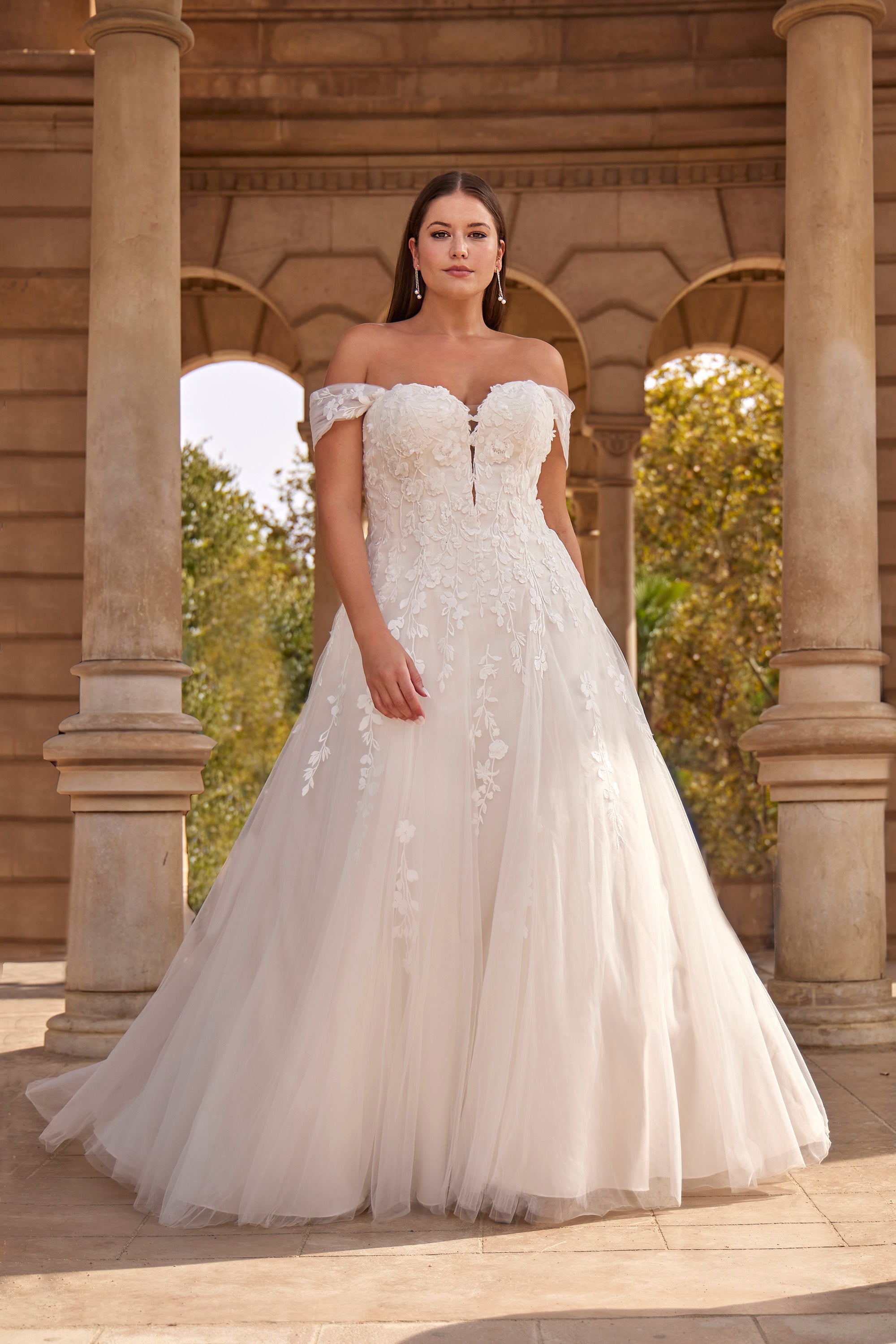 Woman in a white wedding dress standing in front of classical architecture.