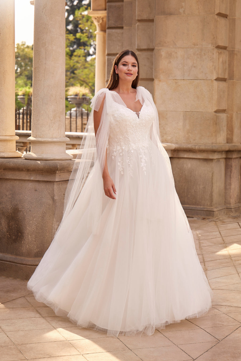 Woman in a white wedding dress standing in front of classical architecture.