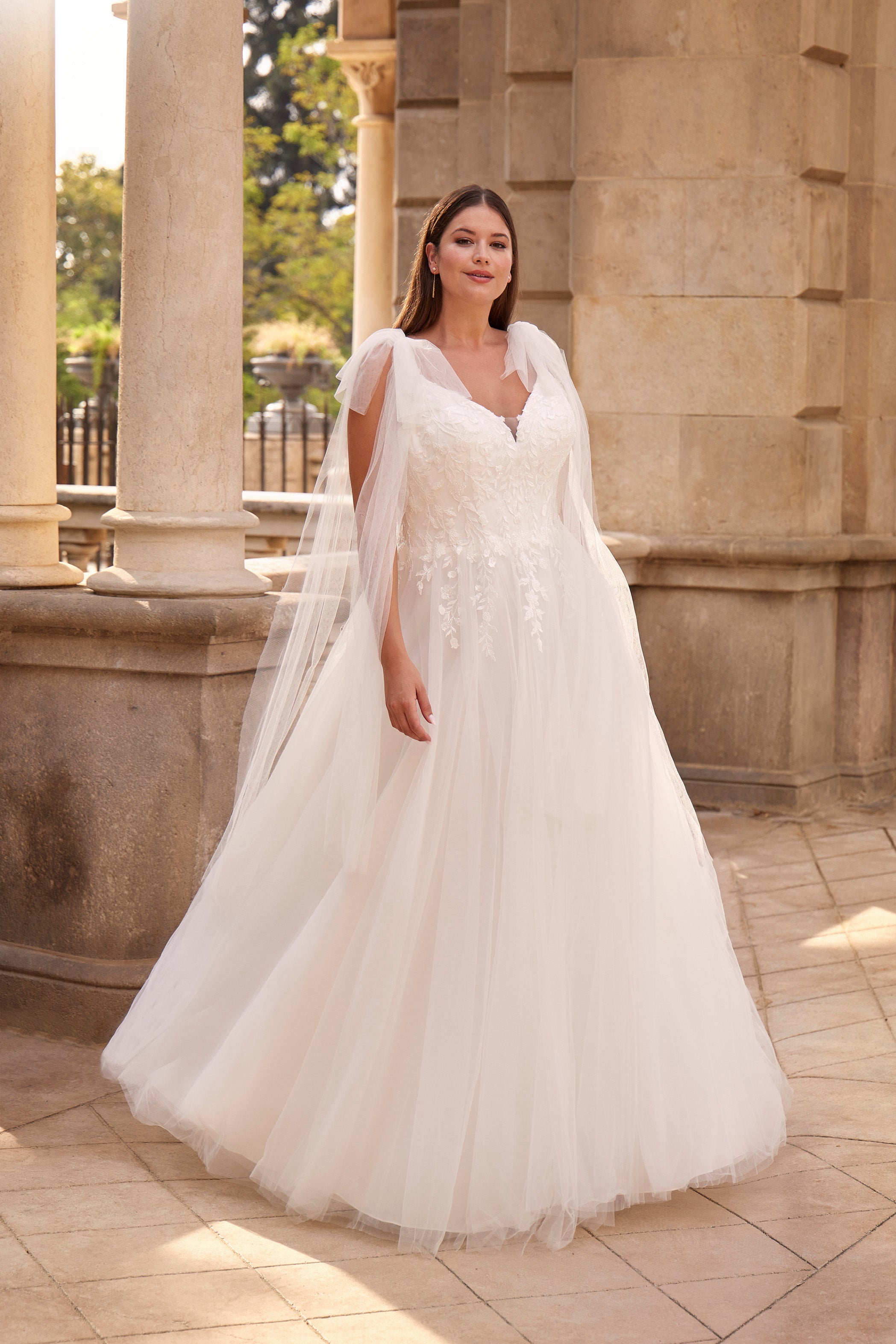 Woman in a white wedding dress standing in front of classical architecture.
