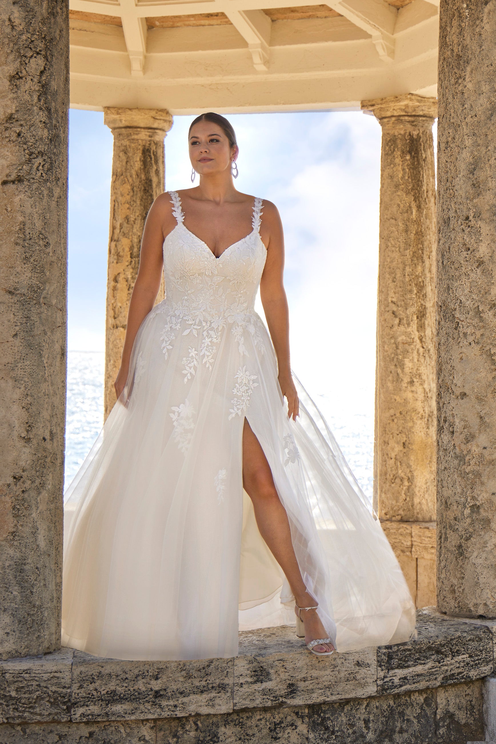 Woman in a white wedding dress standing in front of classical columns.