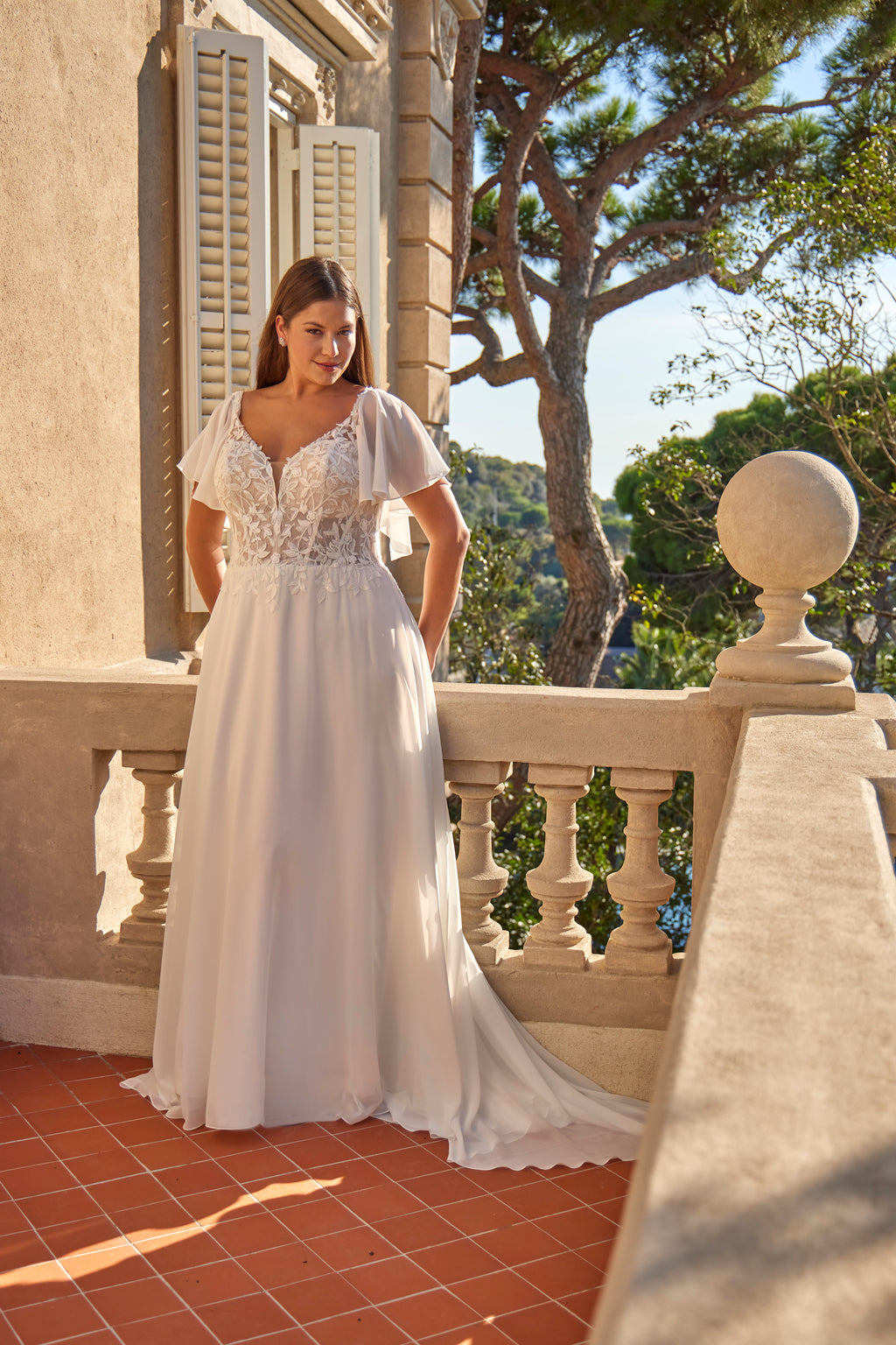 Woman in a white wedding dress standing on a balcony with a scenic background