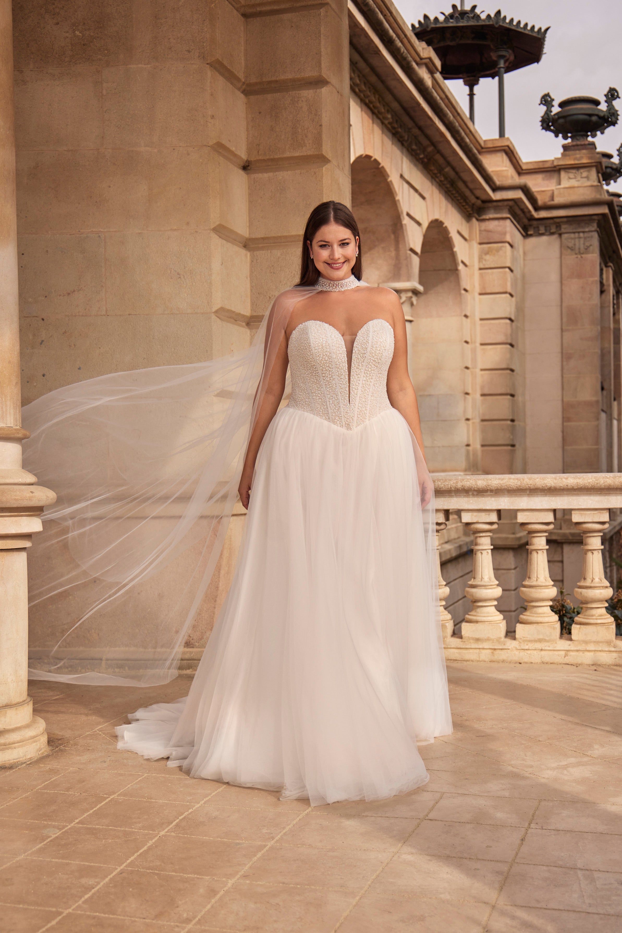 Woman in a white wedding dress standing in front of classical architecture.