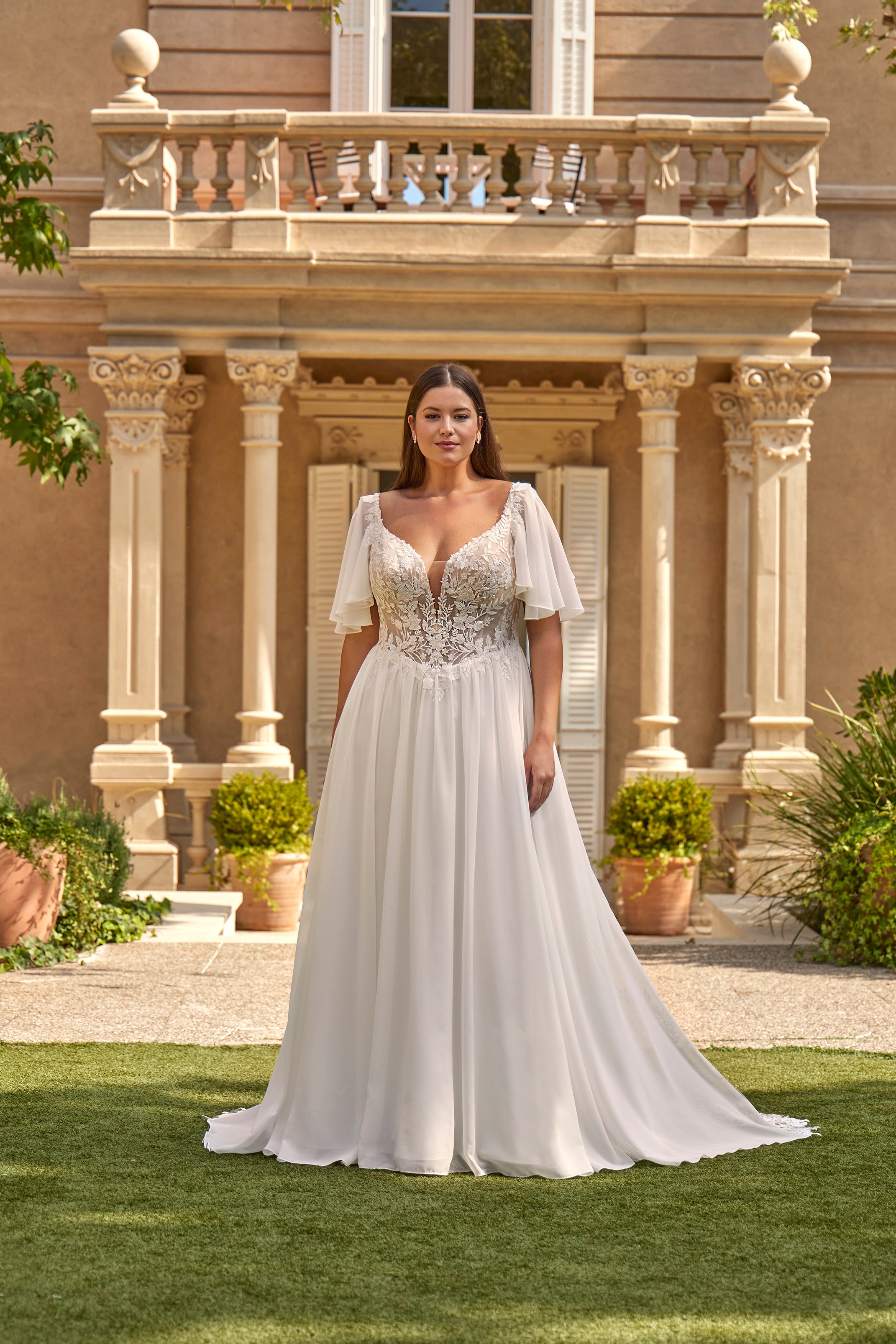Woman in a white wedding dress standing in front of an elegant building with columns.