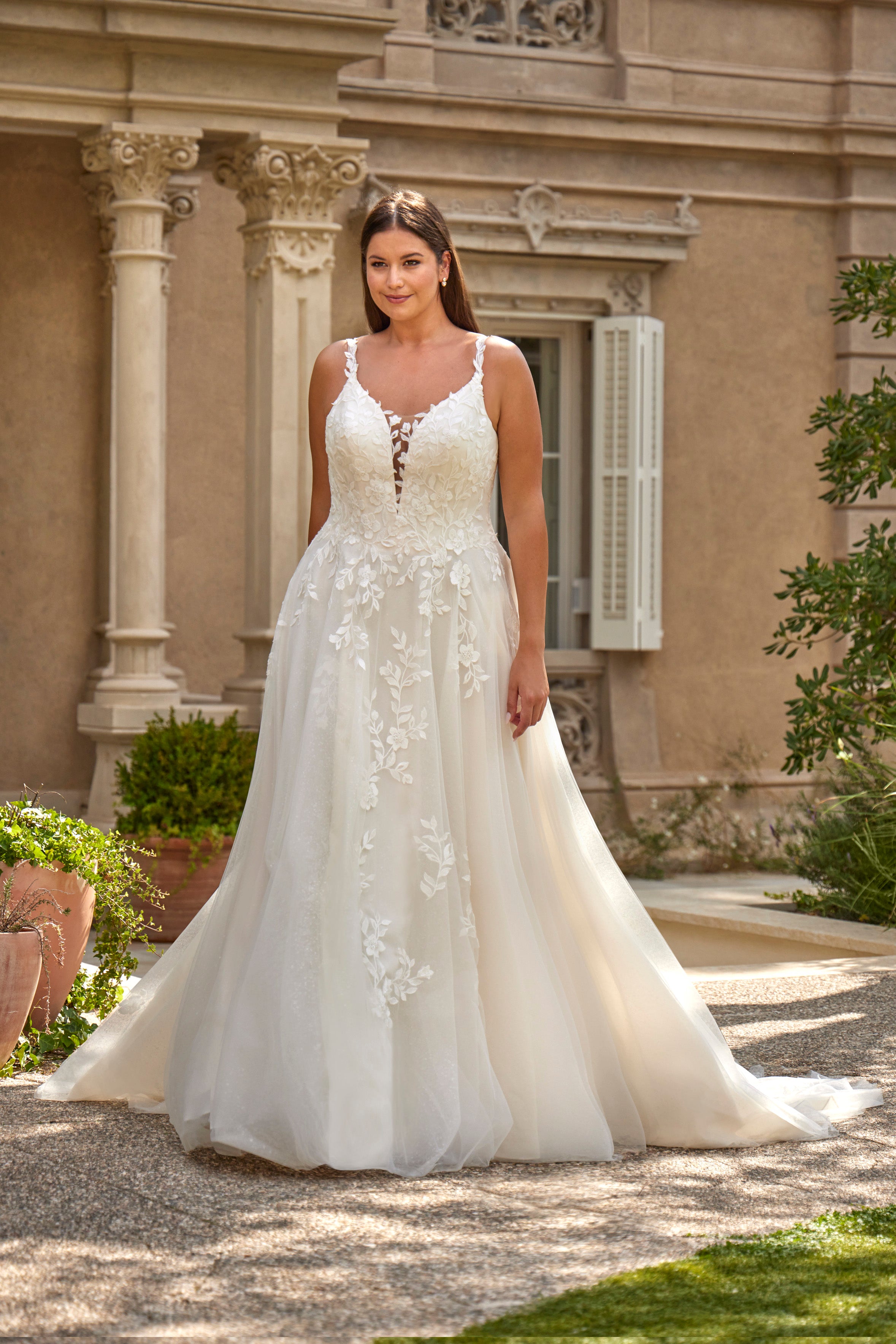 Woman in a white wedding dress standing in front of an elegant building with columns.