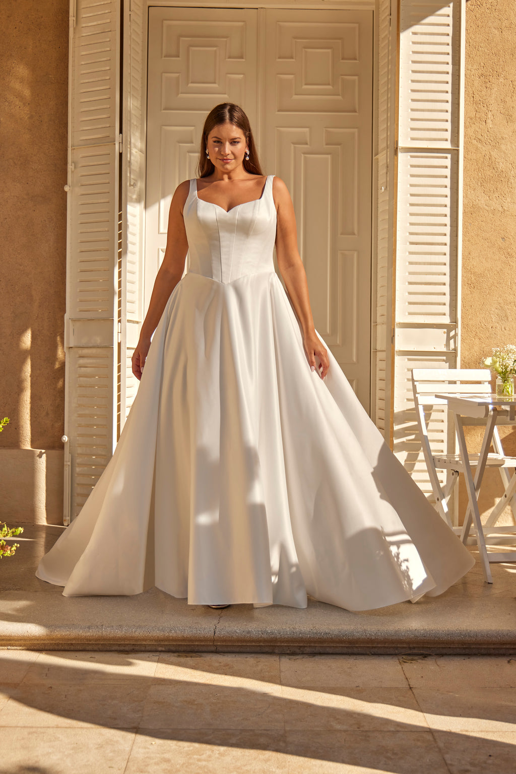 Woman in a white wedding dress standing in front of a building entrance.