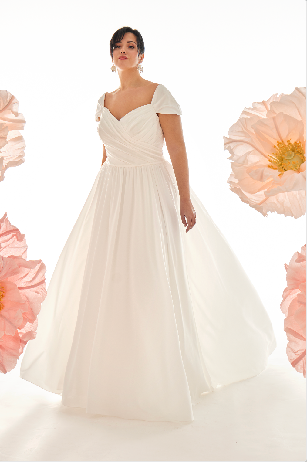 Woman wearing a white wedding dress with pink flowers in the background