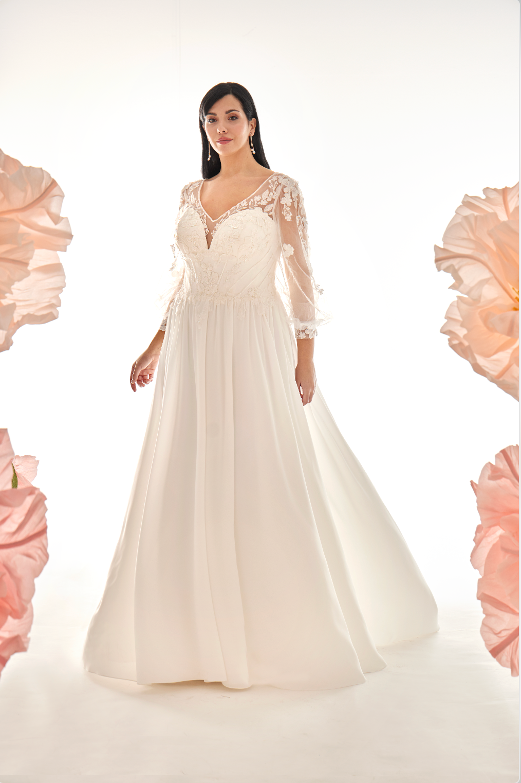 Woman wearing a white wedding dress with floral embellishments on a white background