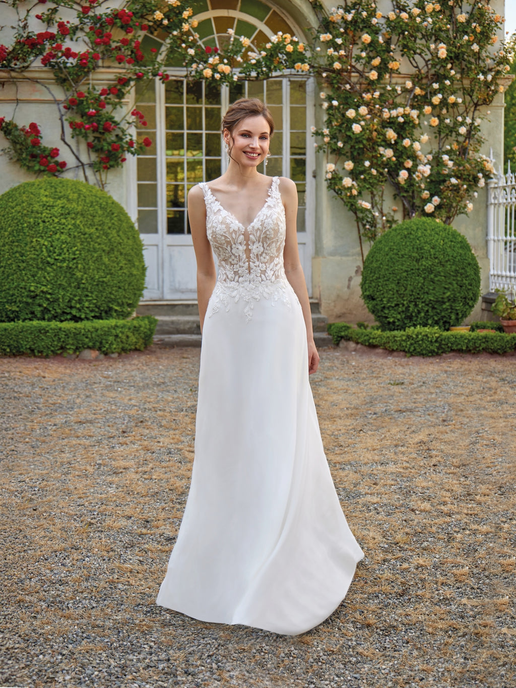 Woman in a white wedding dress standing in a garden with floral decorations.
