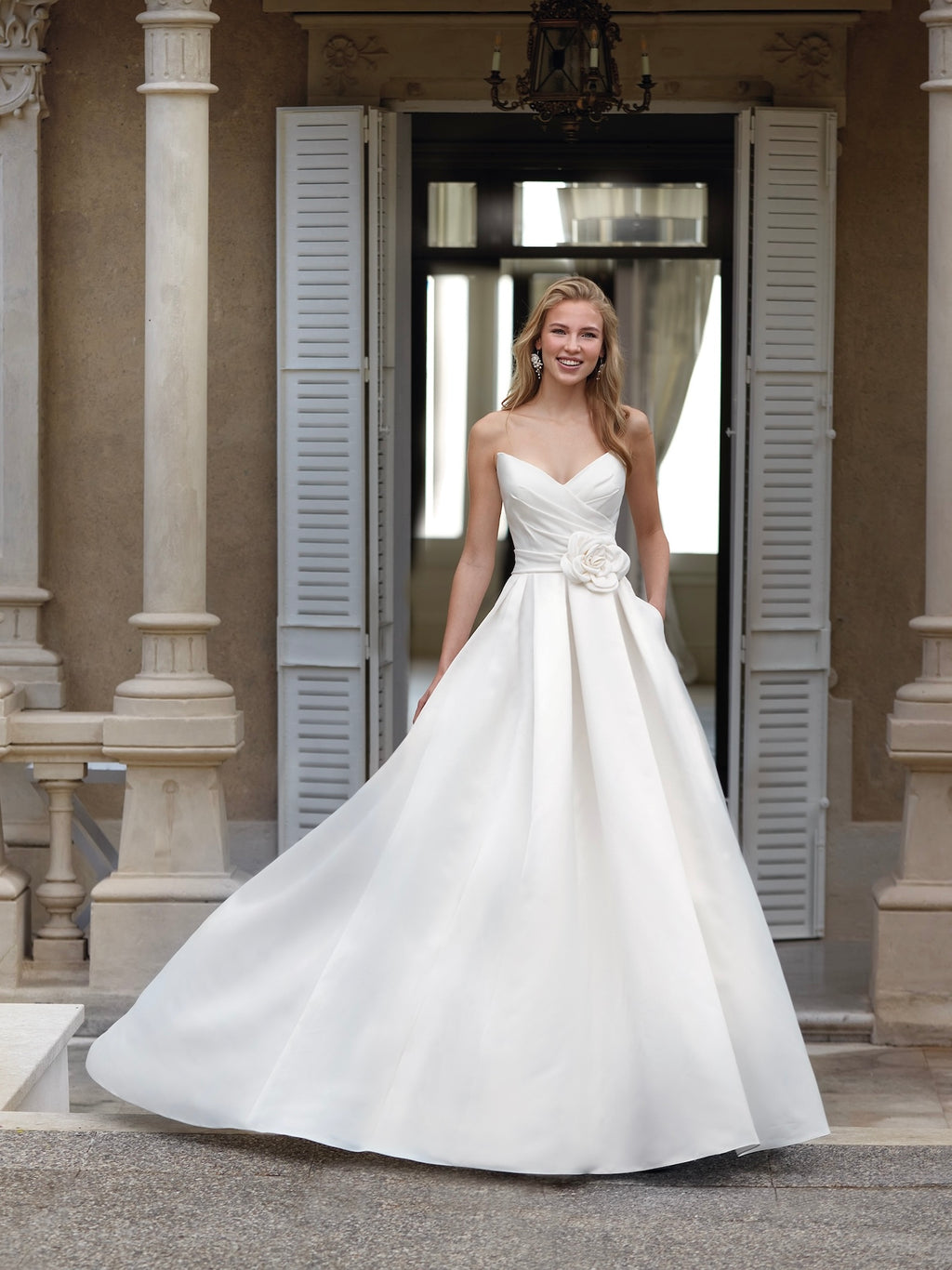 Woman in a white wedding dress standing in front of a doorway.