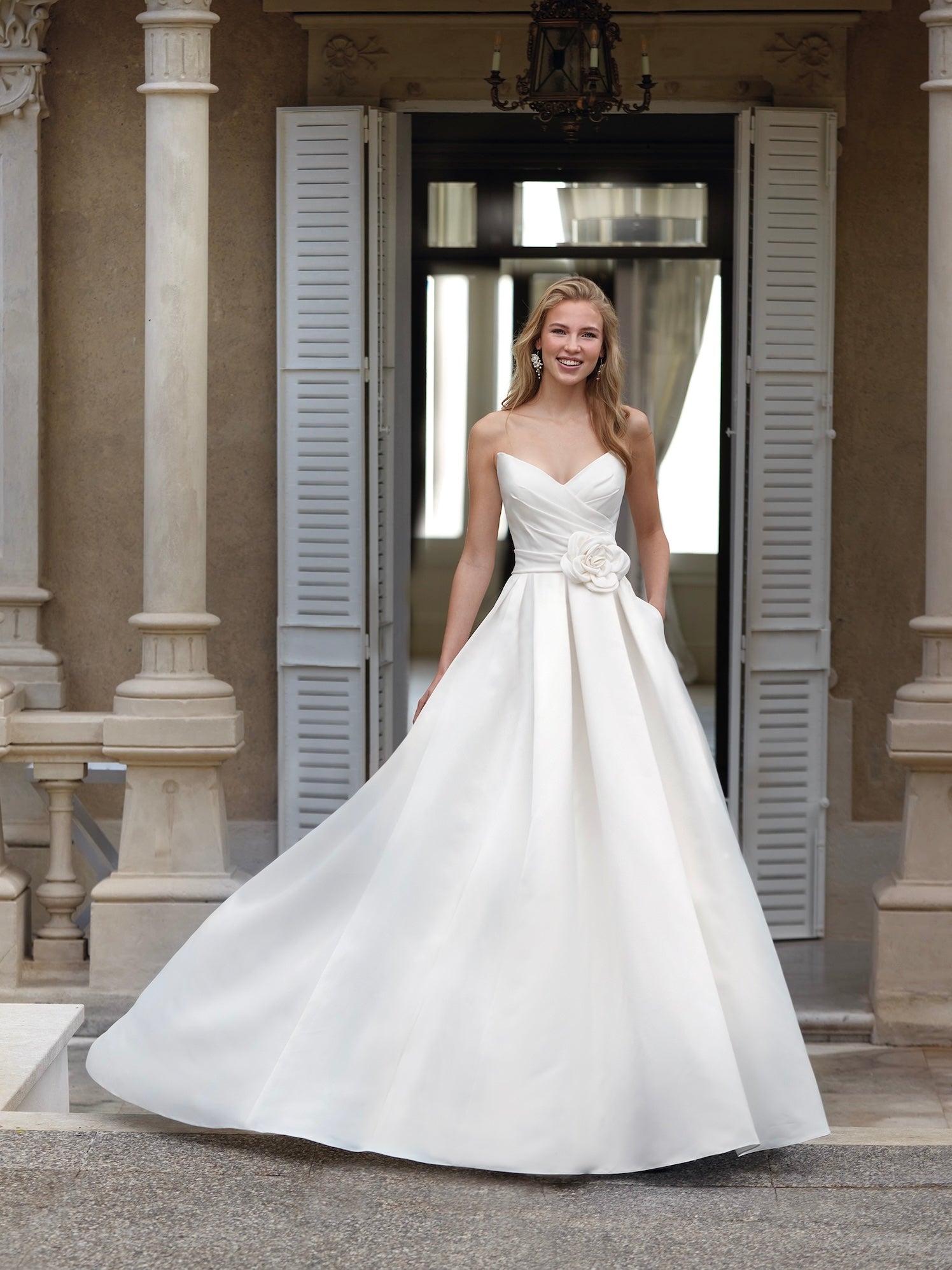 Woman in a white wedding dress standing in front of a doorway.