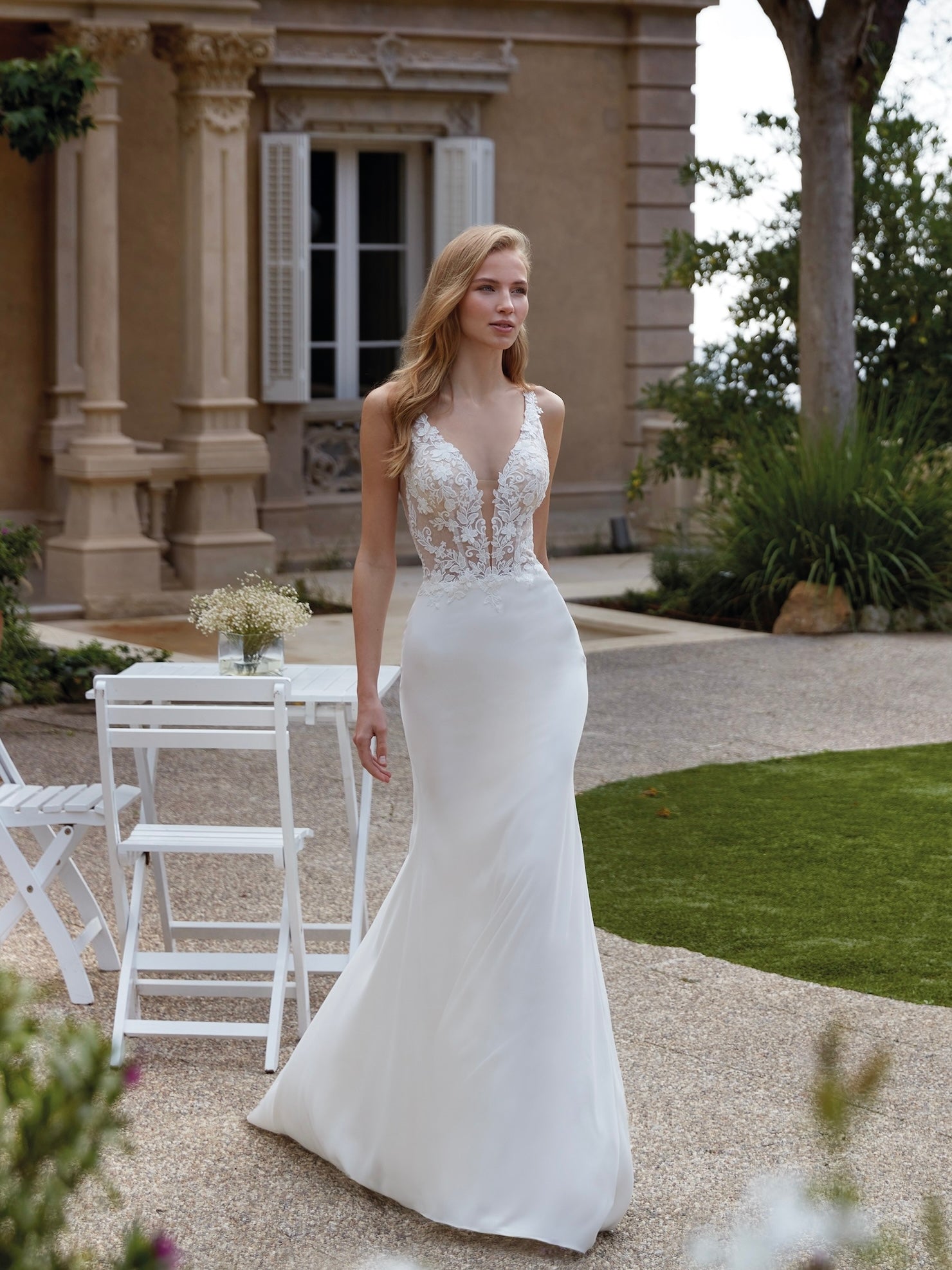 Woman in a white wedding dress standing outdoors near a building with columns.