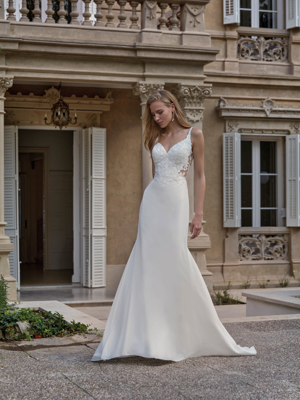 Woman in a white wedding dress standing in front of an elegant building.